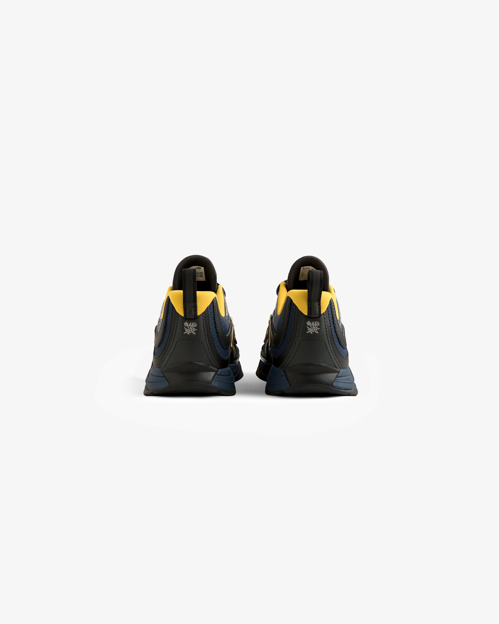 The ALD / New Balance RC56 sneakers in dark blue and yellow are shown from the back on a plain white background.