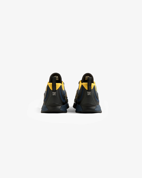 The ALD / New Balance RC56 sneakers in dark blue and yellow are shown from the back on a plain white background.