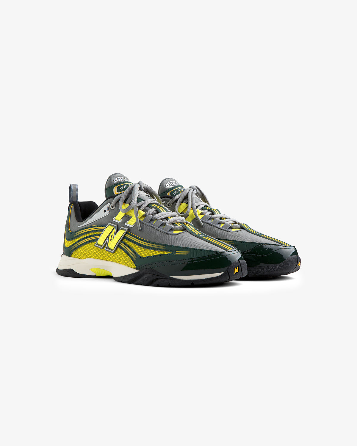 Two ALD / New Balance RC56 sneakers in green, yellow, and gray with laces, side by side on a white background.