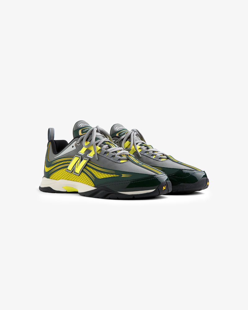 Two ALD / New Balance RC56 sneakers in green, yellow, and gray with laces, side by side on a white background.