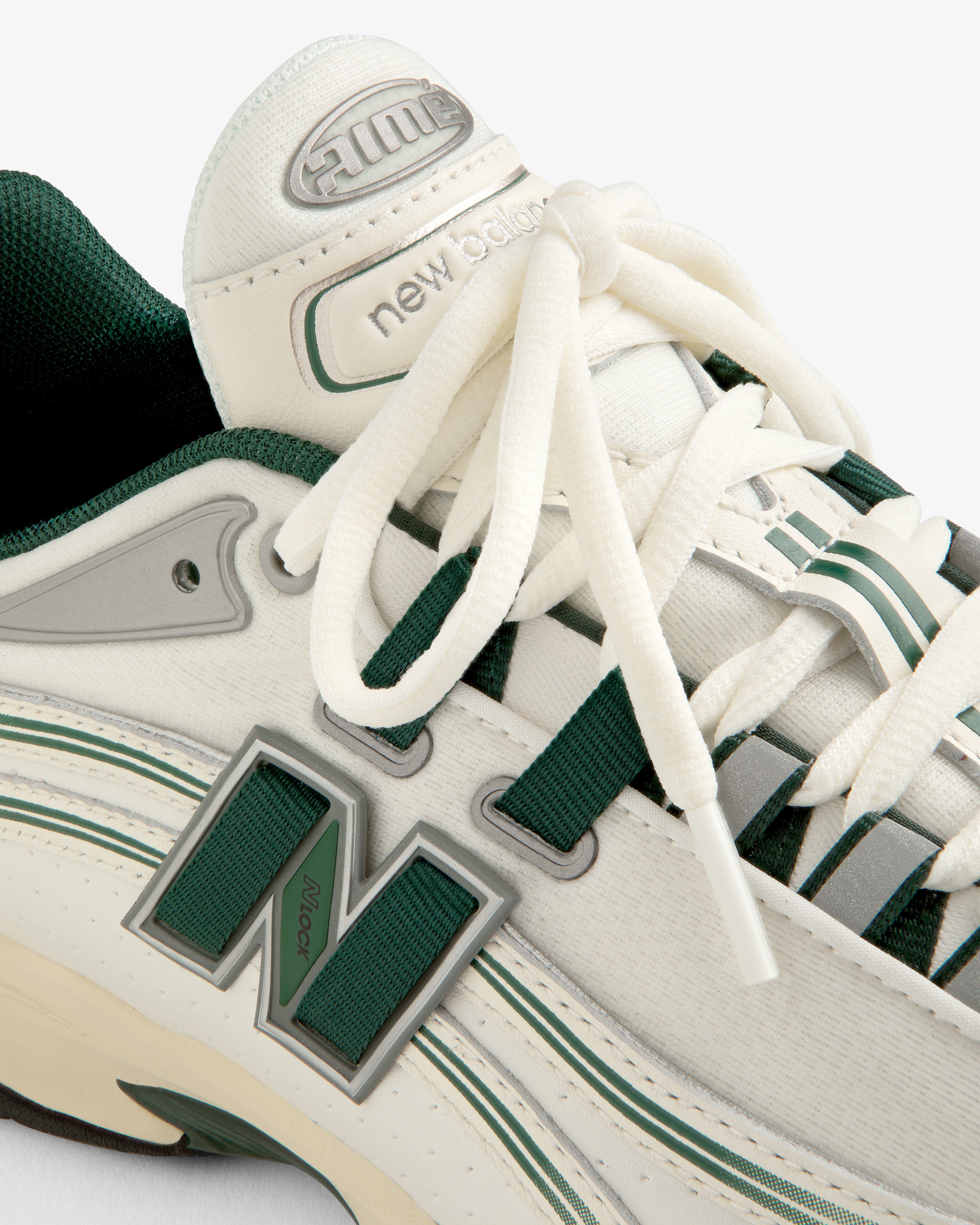 Close-up of the ALD / New Balance RC56 sneaker in white with green accents, highlighting the logo and tongue details.