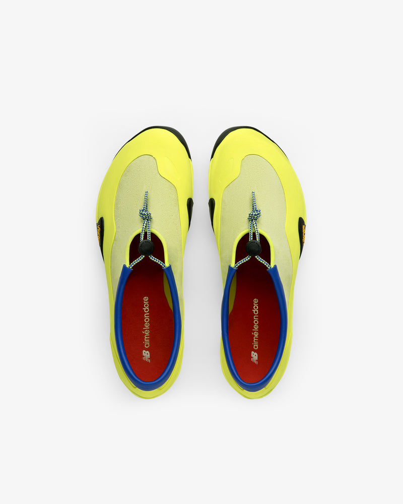 Top view of ALD / New Balance MT10T Sport Shoes—yellow slip-ons with blue trim, red insoles, on white background.