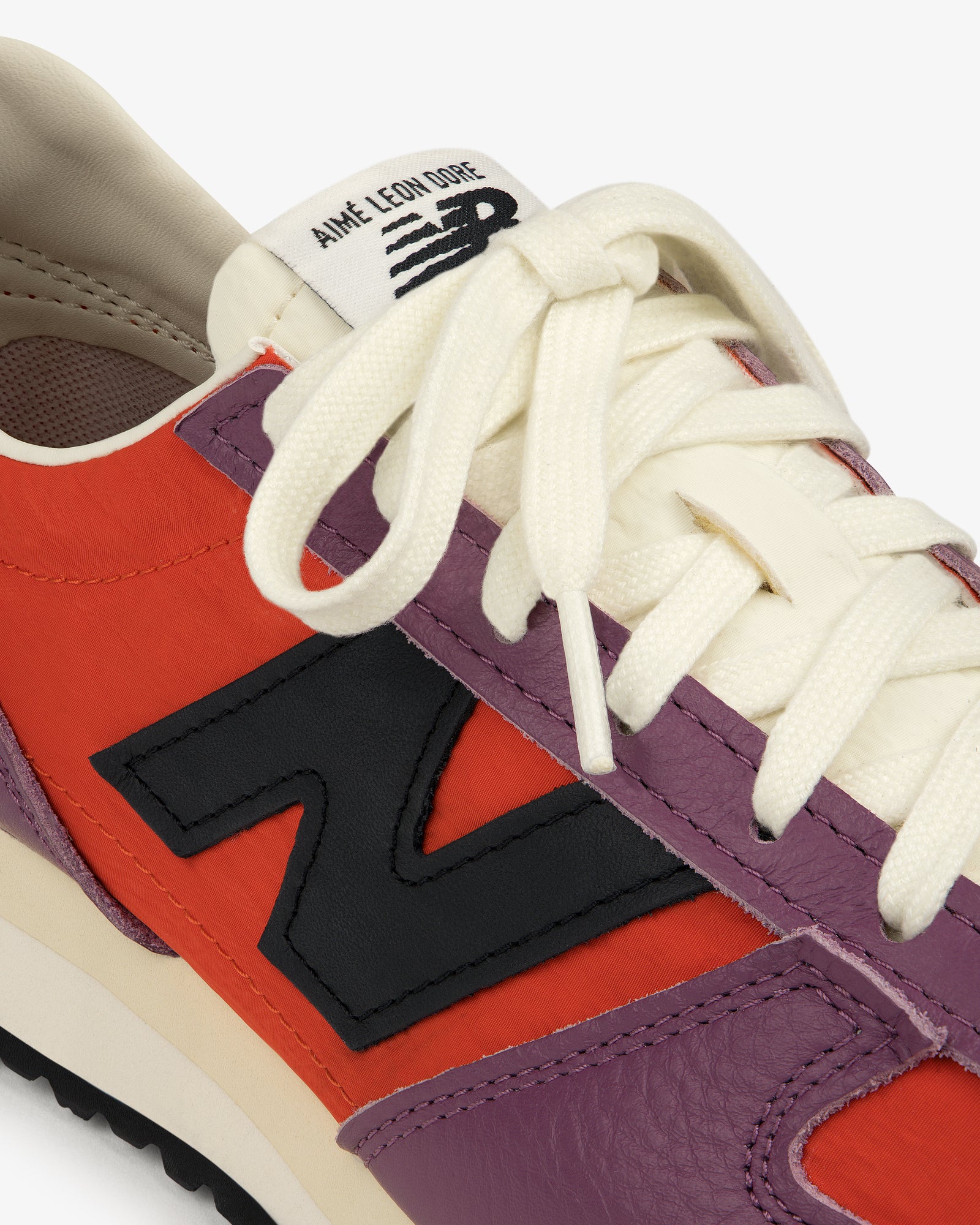 Close-up of the ALD / New Balance 471 sneaker with cream laces, purple and red panels, and a black N logo.