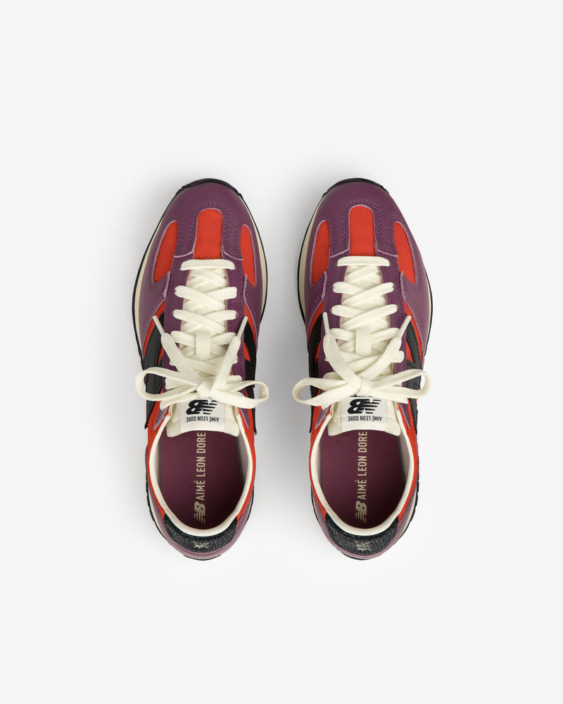 A pair of ALD / New Balance 471 sneakers in red, purple, and black with white laces, viewed from above.