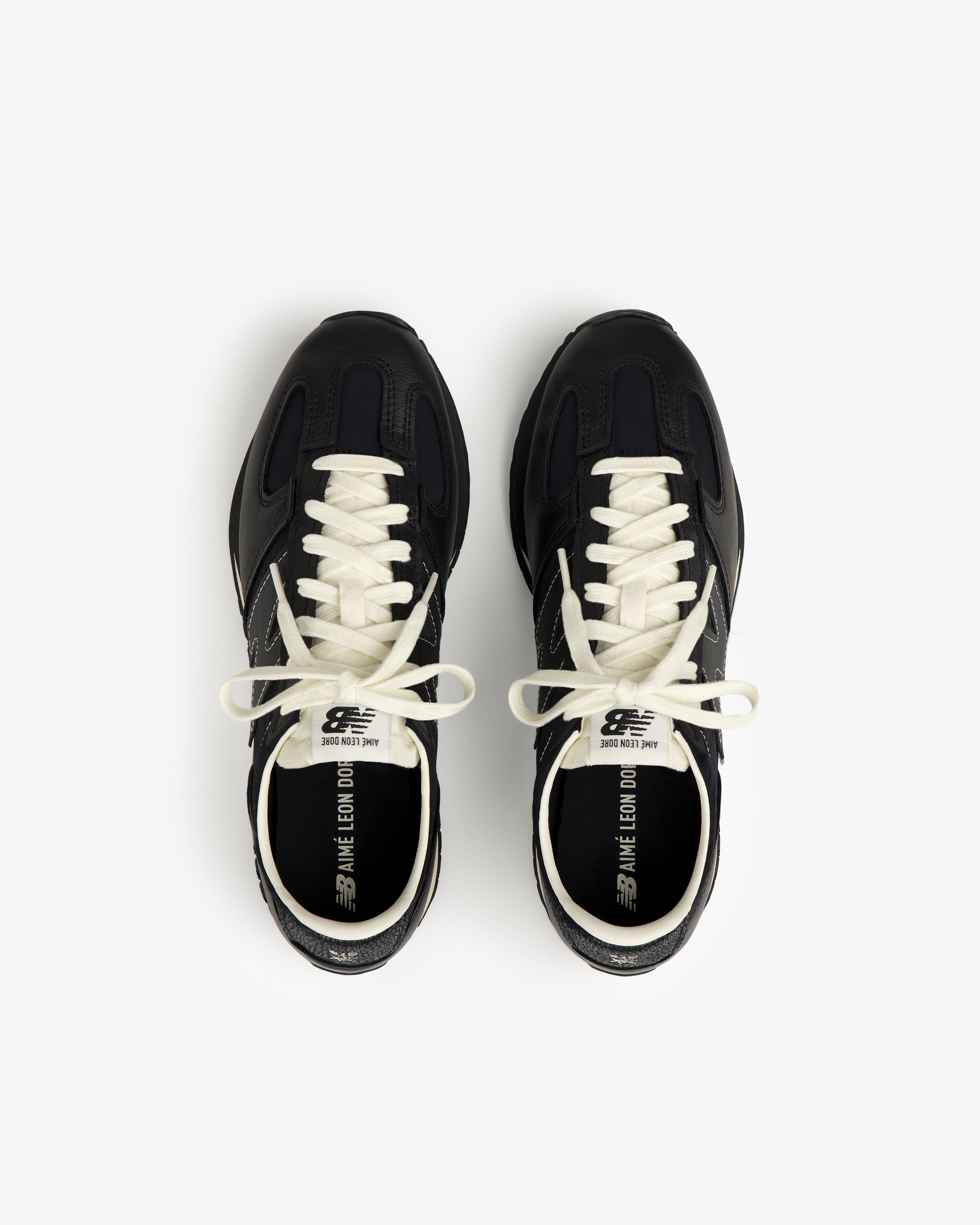 A pair of ALD / New Balance 471 black sneakers with white laces, viewed from above on a white backdrop.