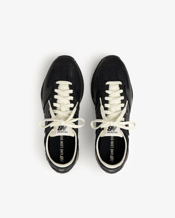 A pair of ALD / New Balance 471 black sneakers with white laces, viewed from above on a white backdrop.