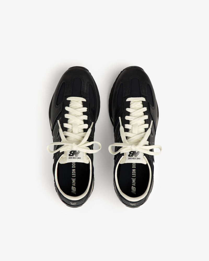 A pair of ALD / New Balance 471 black sneakers with white laces, viewed from above on a white backdrop.