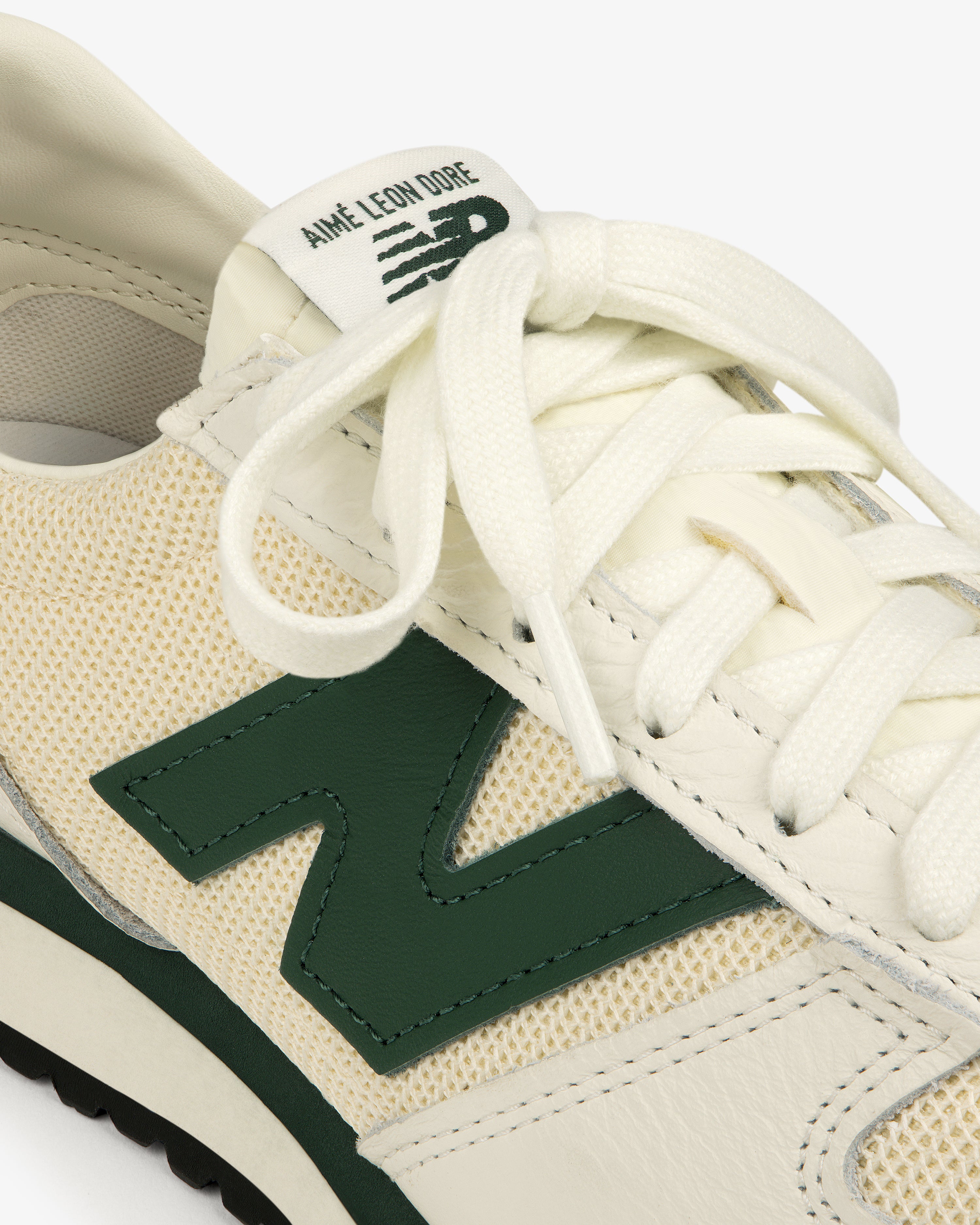 Close-up of a cream and green ALD / New Balance 471 sneaker with Aimé Leon Dore branding on the tongue.