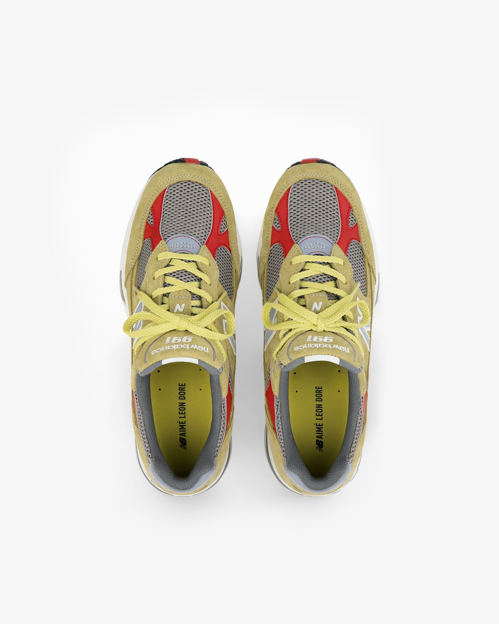 ALD / New Balance Made in UK 991 sneakers with yellow laces, gray mesh, red and yellow accents, top view on white.