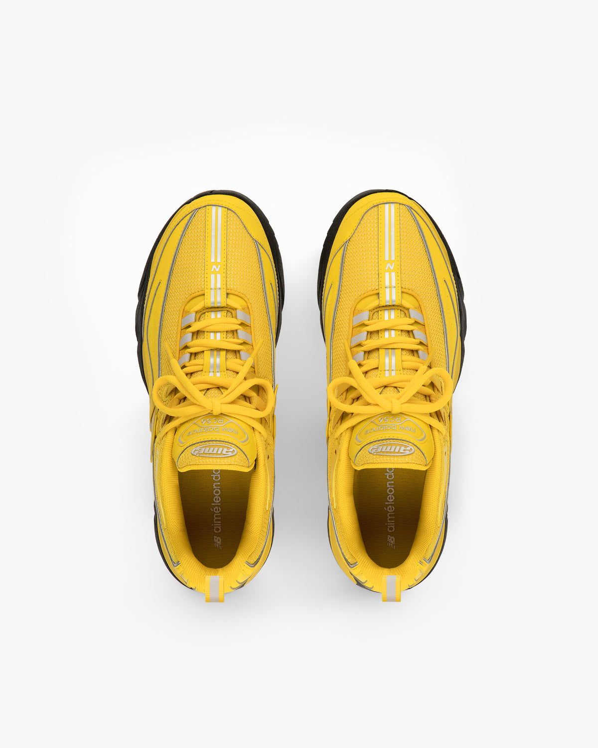 A pair of ALD / New Balance RC56 yellow athletic sneakers with black soles, viewed from above on white.