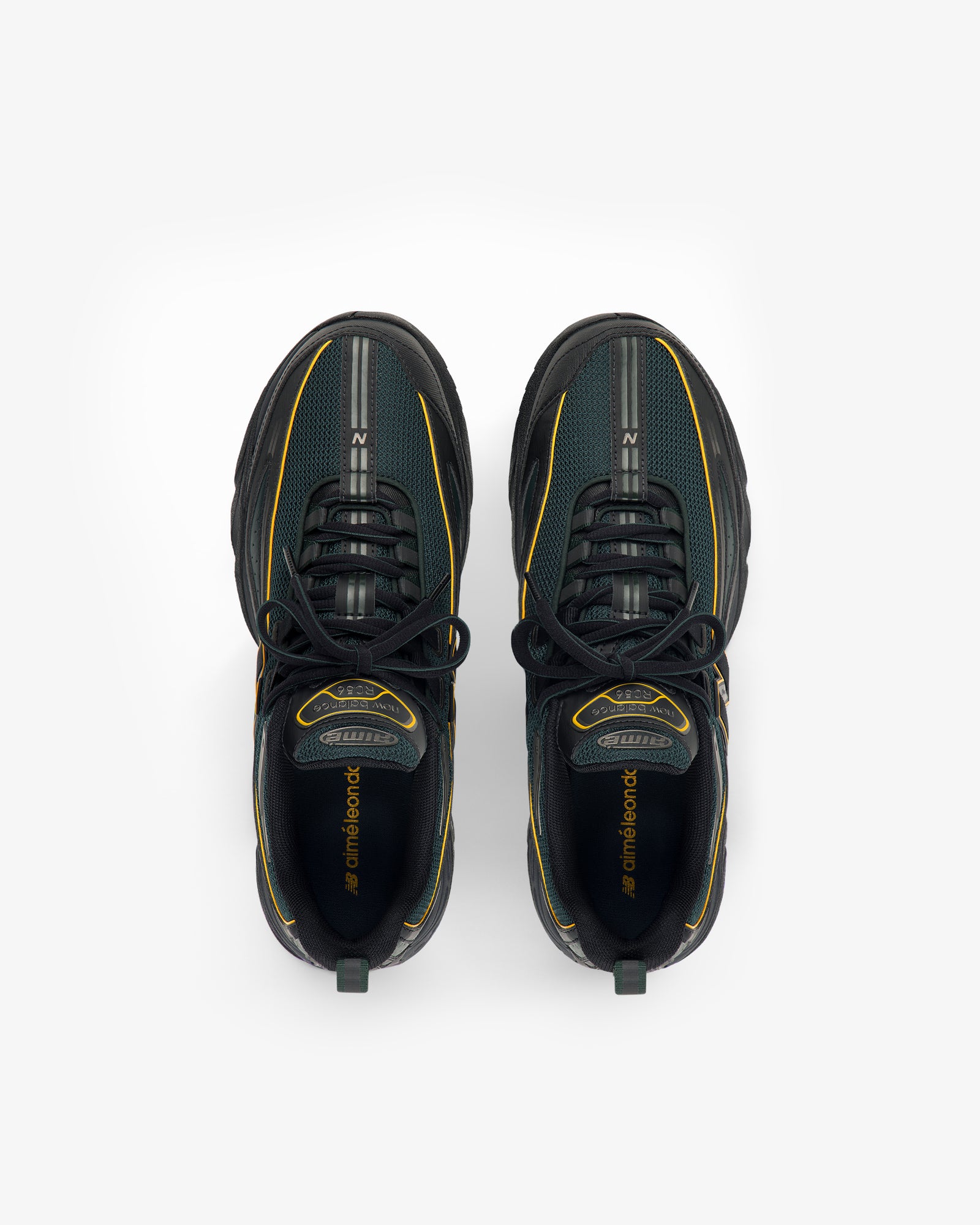 A pair of ALD / New Balance RC56 black sneakers with yellow accents, shown from above on a white background.