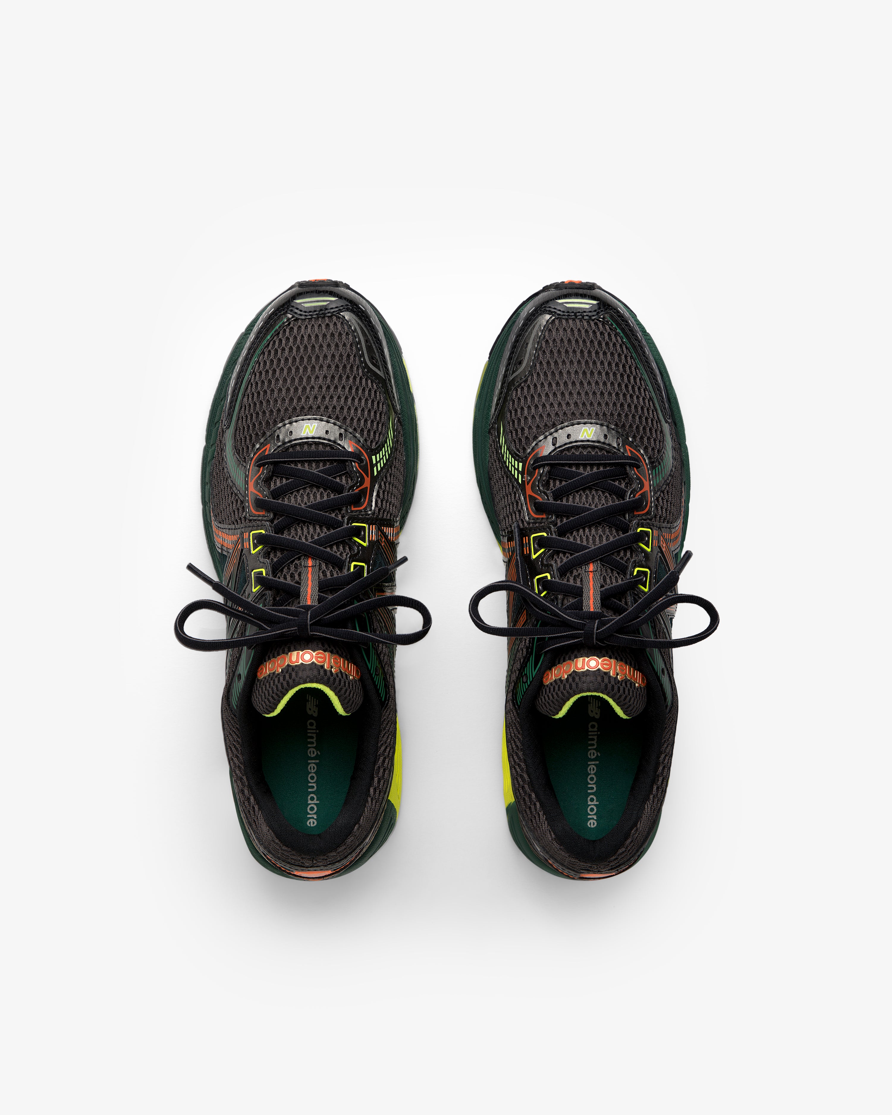 ALD / New Balance 860v2 black sneakers with green, orange, and yellow accents, top view on white background.