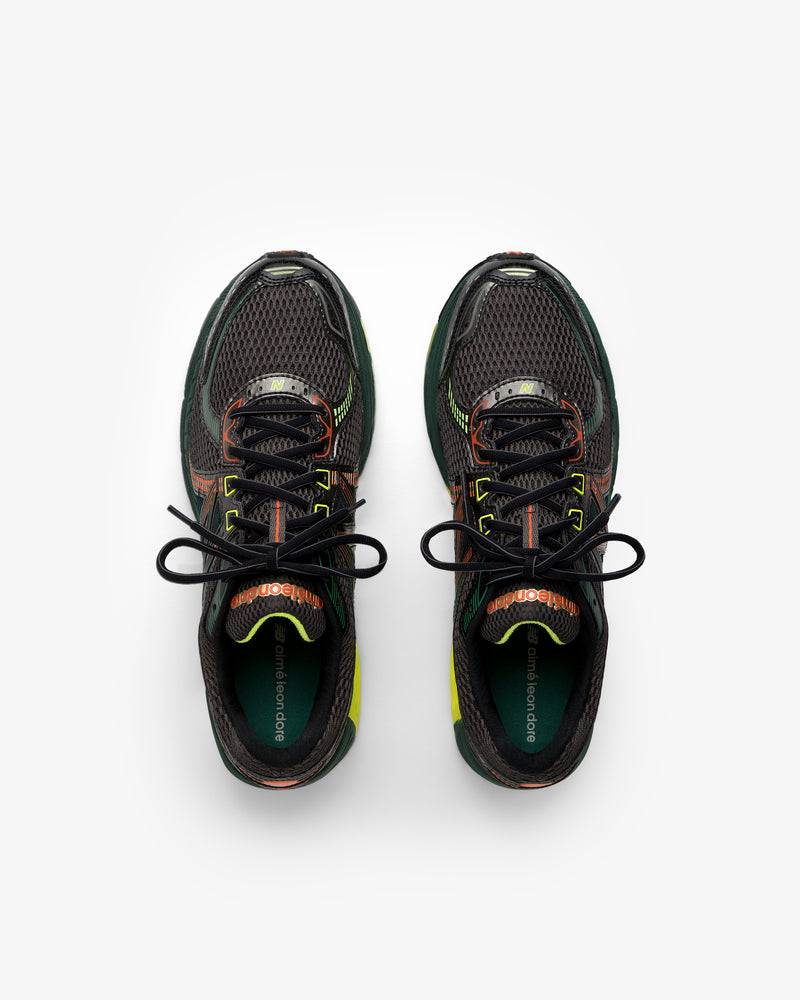 ALD / New Balance 860v2 black sneakers with green, orange, and yellow accents, top view on white background.