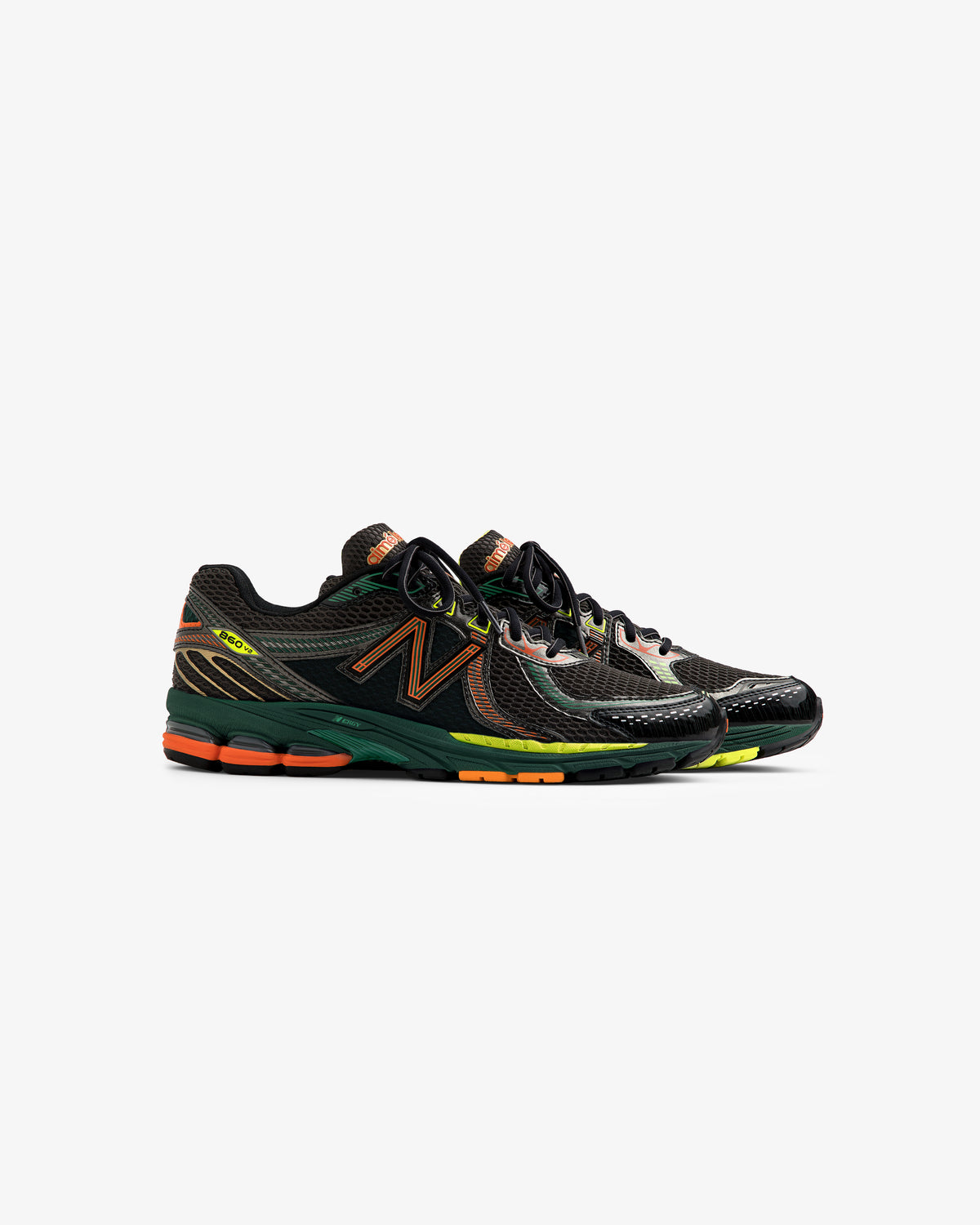 A pair of ALD / New Balance 860v2 sneakers in black and green with orange and yellow accents on a white background.