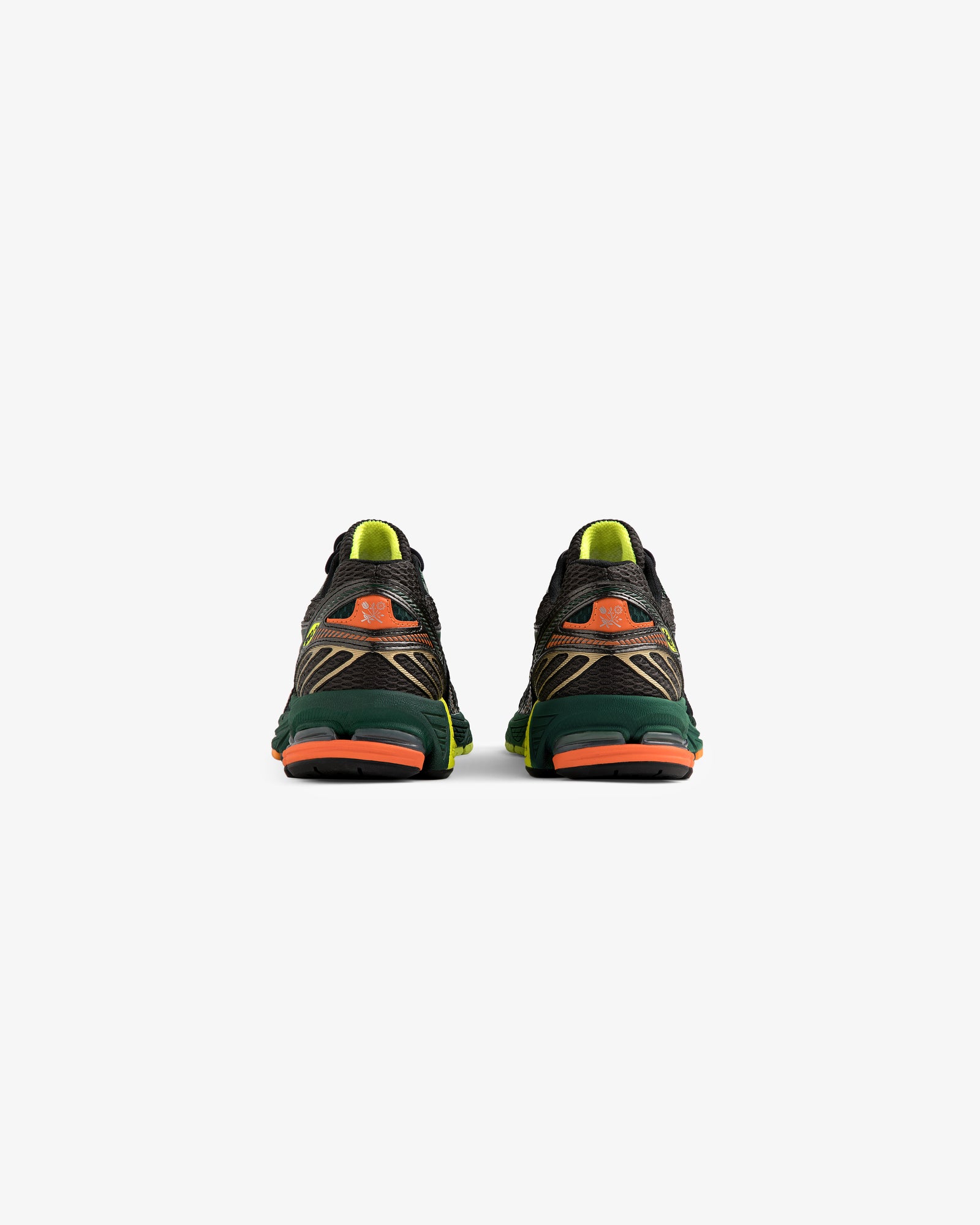 The ALD / New Balance 860v2 running shoes shown from the back have green, orange, and yellow accents on white.