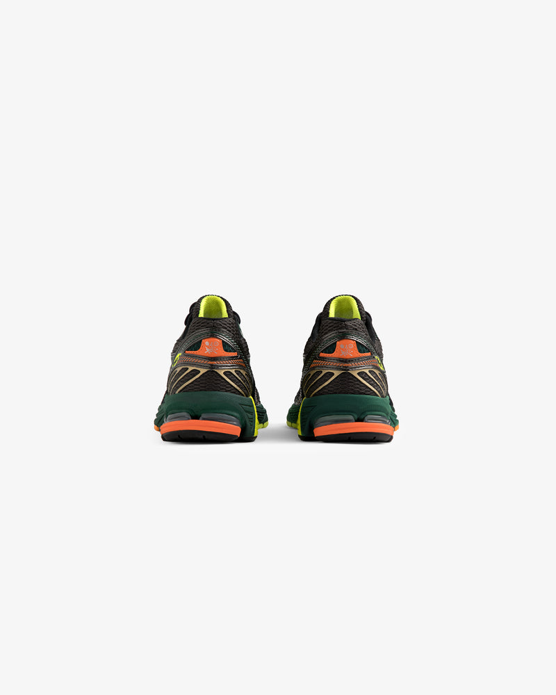 The ALD / New Balance 860v2 running shoes shown from the back have green, orange, and yellow accents on white.