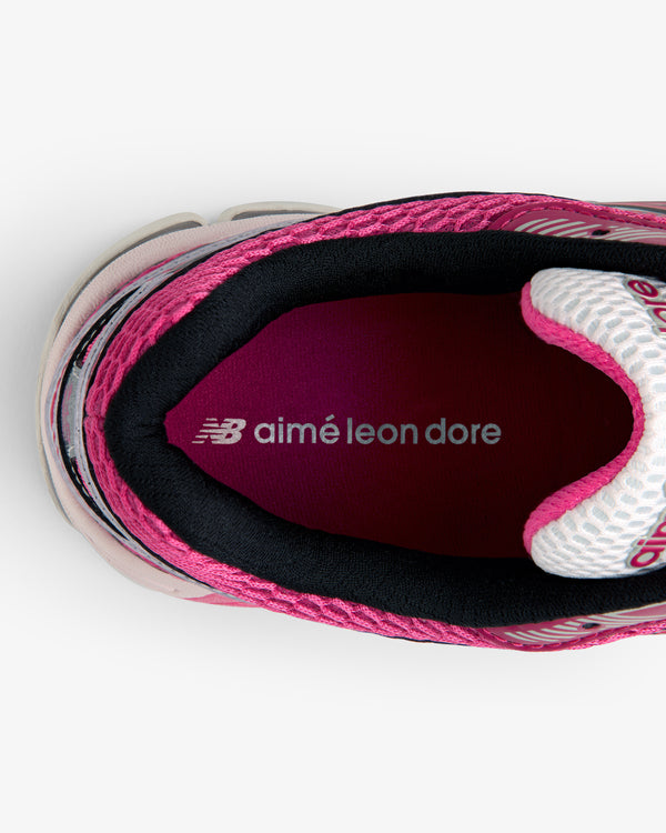 Top view of a pink ALD / New Balance 860v2 sneaker with aimé leon dore text on the maroon insole.