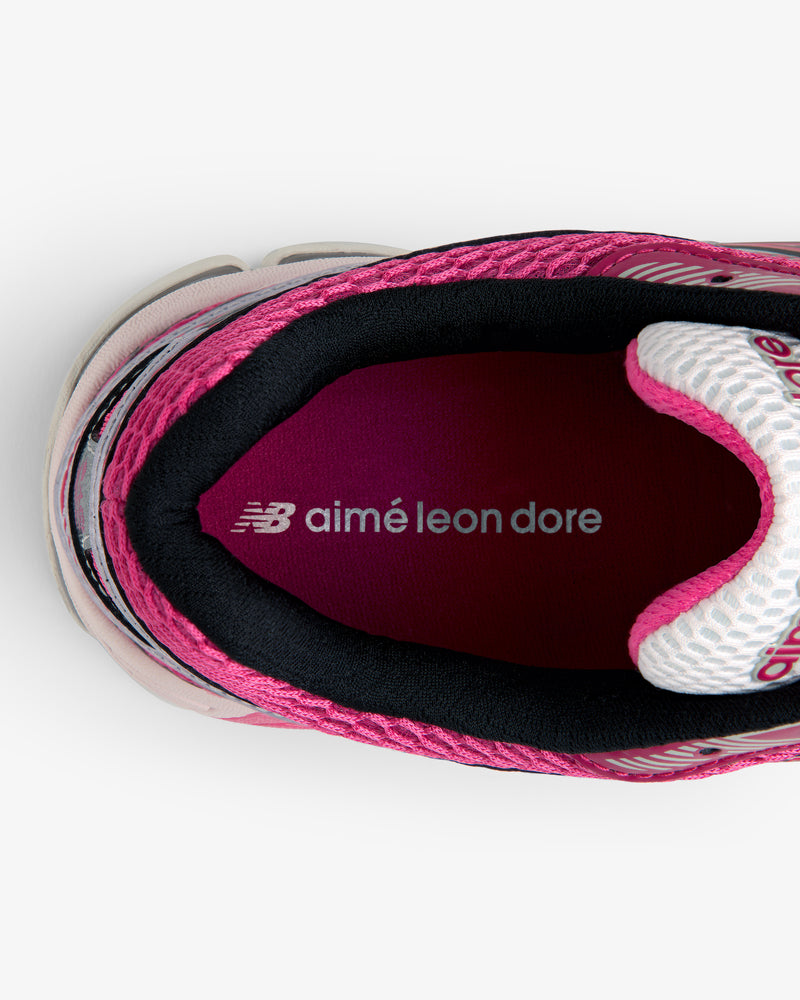Top view of a pink ALD / New Balance 860v2 sneaker with aimé leon dore text on the maroon insole.