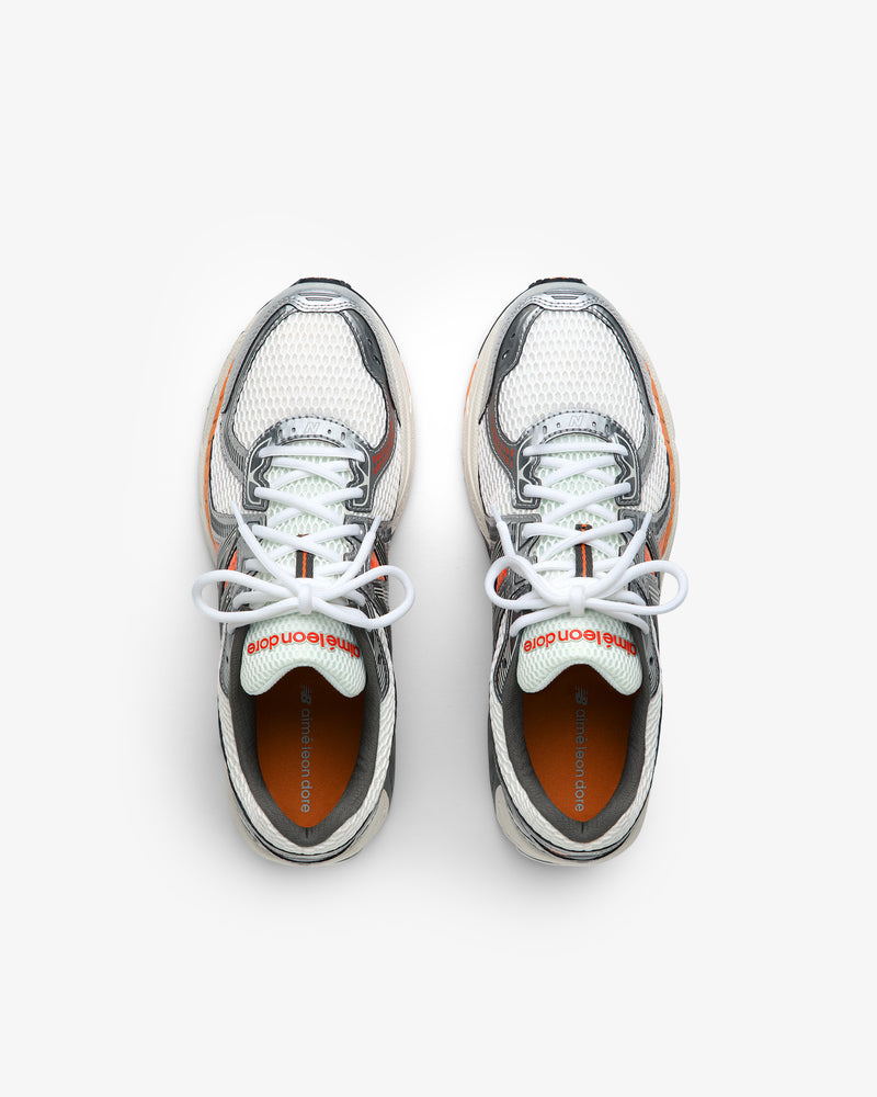 ALD / New Balance 860v2 white mesh sneakers with gray and orange accents, top view on a white background.