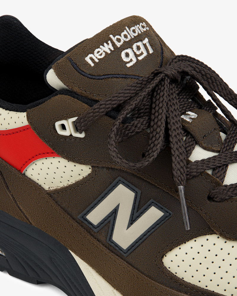 Close-up of a brown ALD / New Balance Made in UK 991 sneaker with red accent and visible logo on side and tongue.