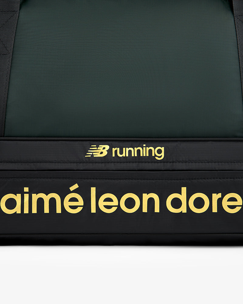 Close-up of the ALD / New Balance Travel Duffle Bag featuring yellow logos on a black background.