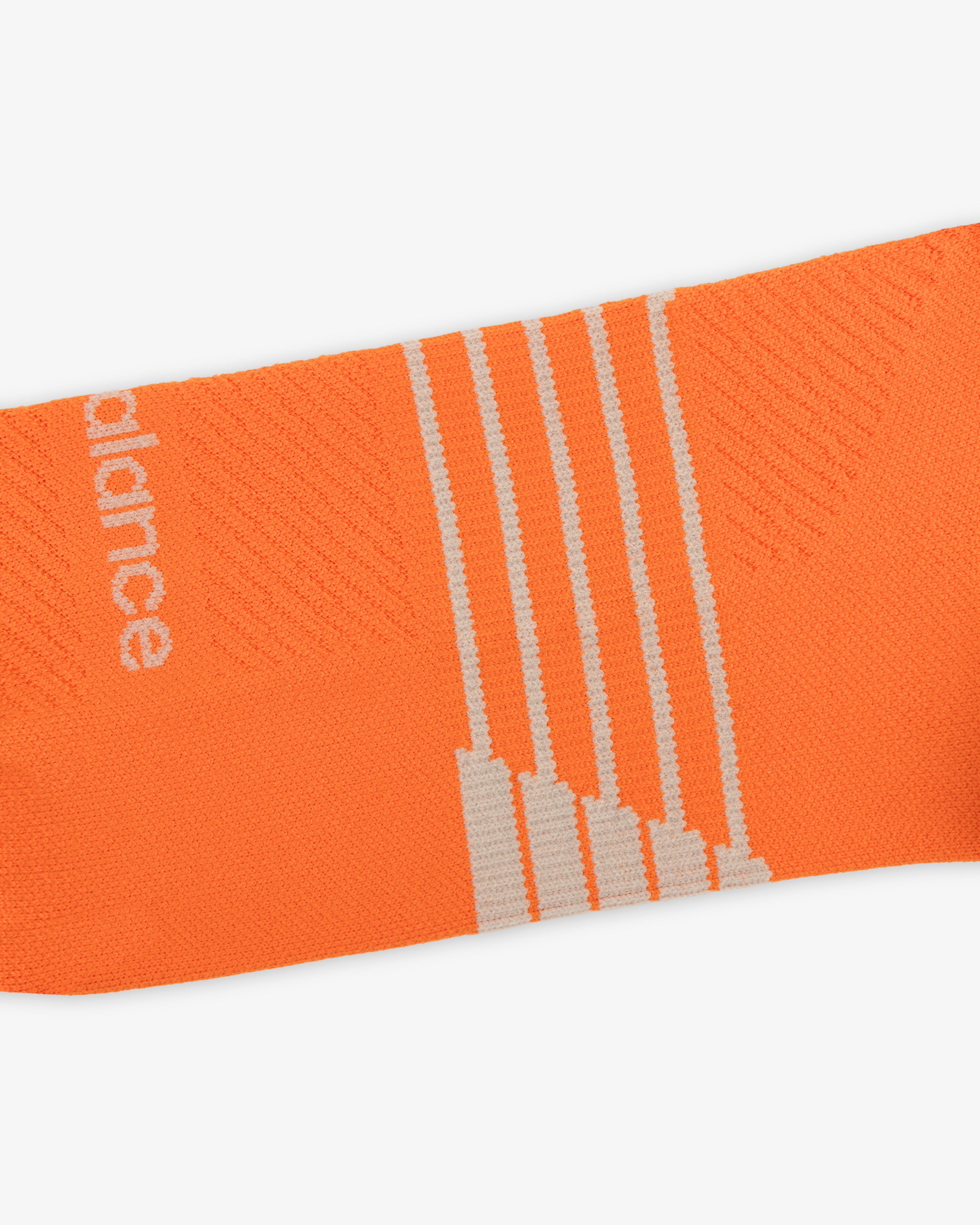 Close-up of ALD / New Balance Running Crew Sock—orange with white stripes and partial white text on the side.