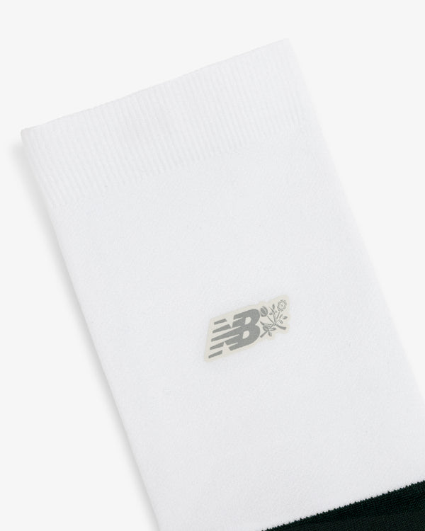 ALD / New Balance Running Crew Sock: white with ribbed top, small gray NB logo, and flower graphic at center.