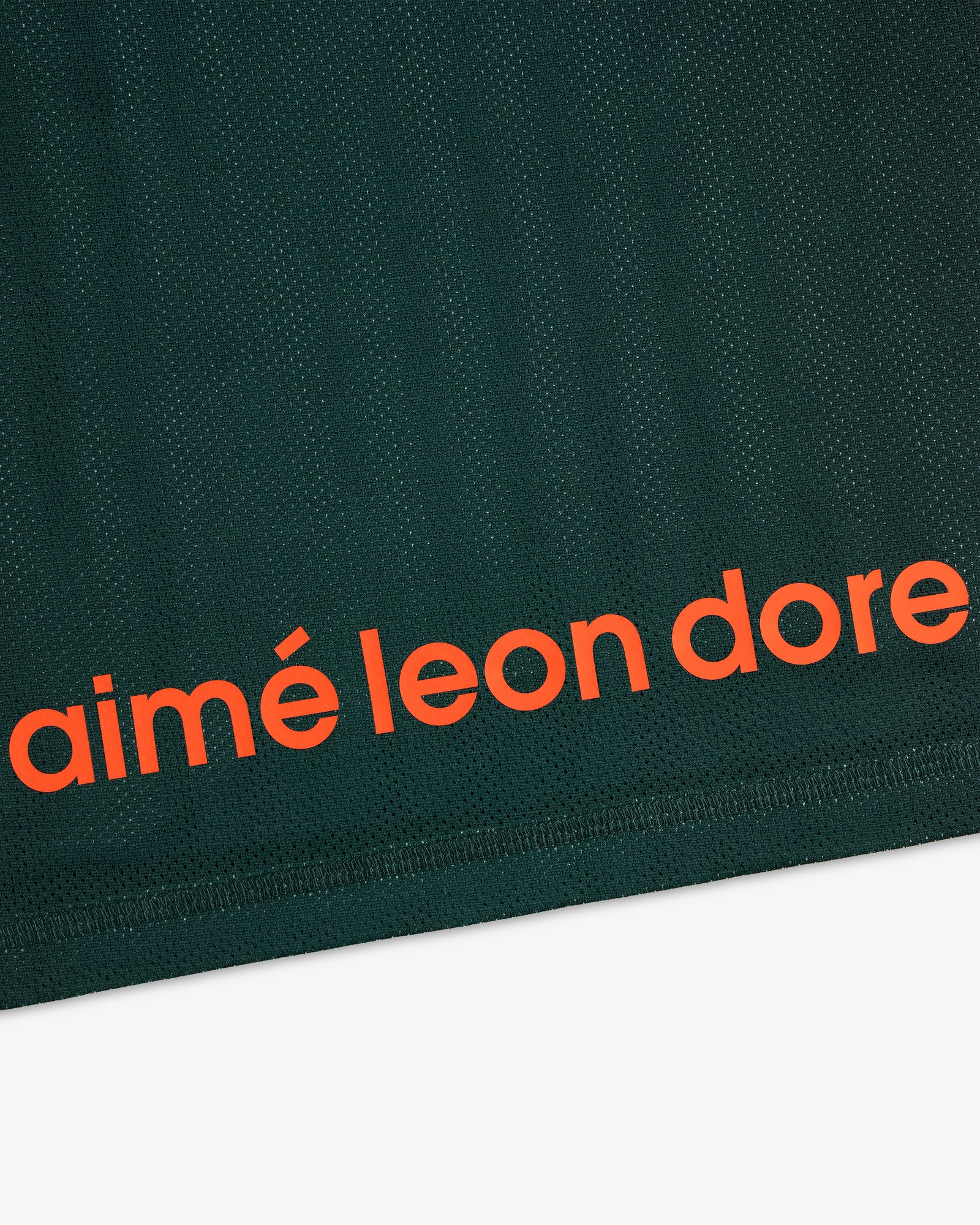 Close-up of dark green ALD / New Balance Running Gradient Singlet with bold orange aimé leon dore near the edge.
