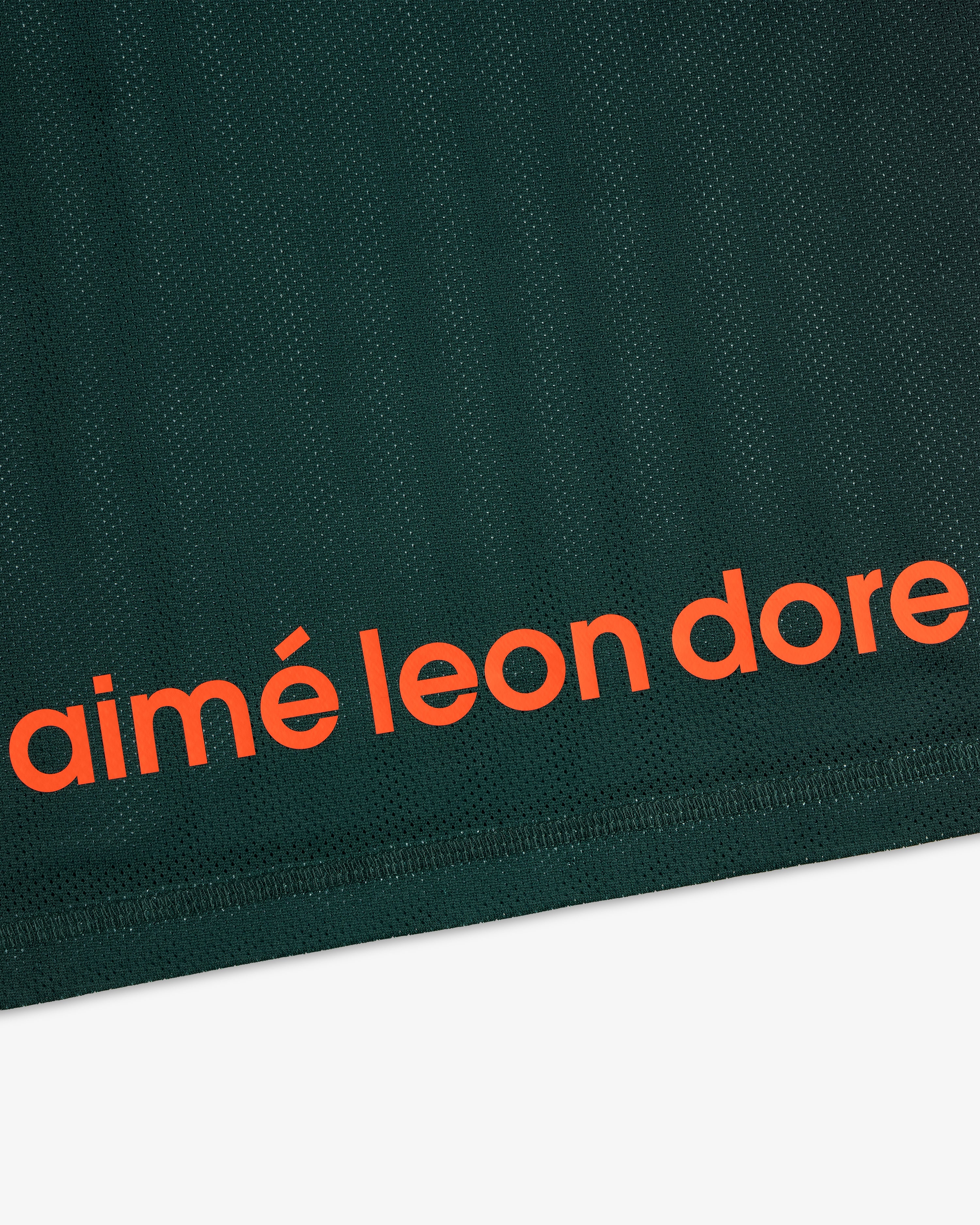 Close-up of dark green ALD / New Balance Running Gradient Singlet with bold orange aimé leon dore near the edge.