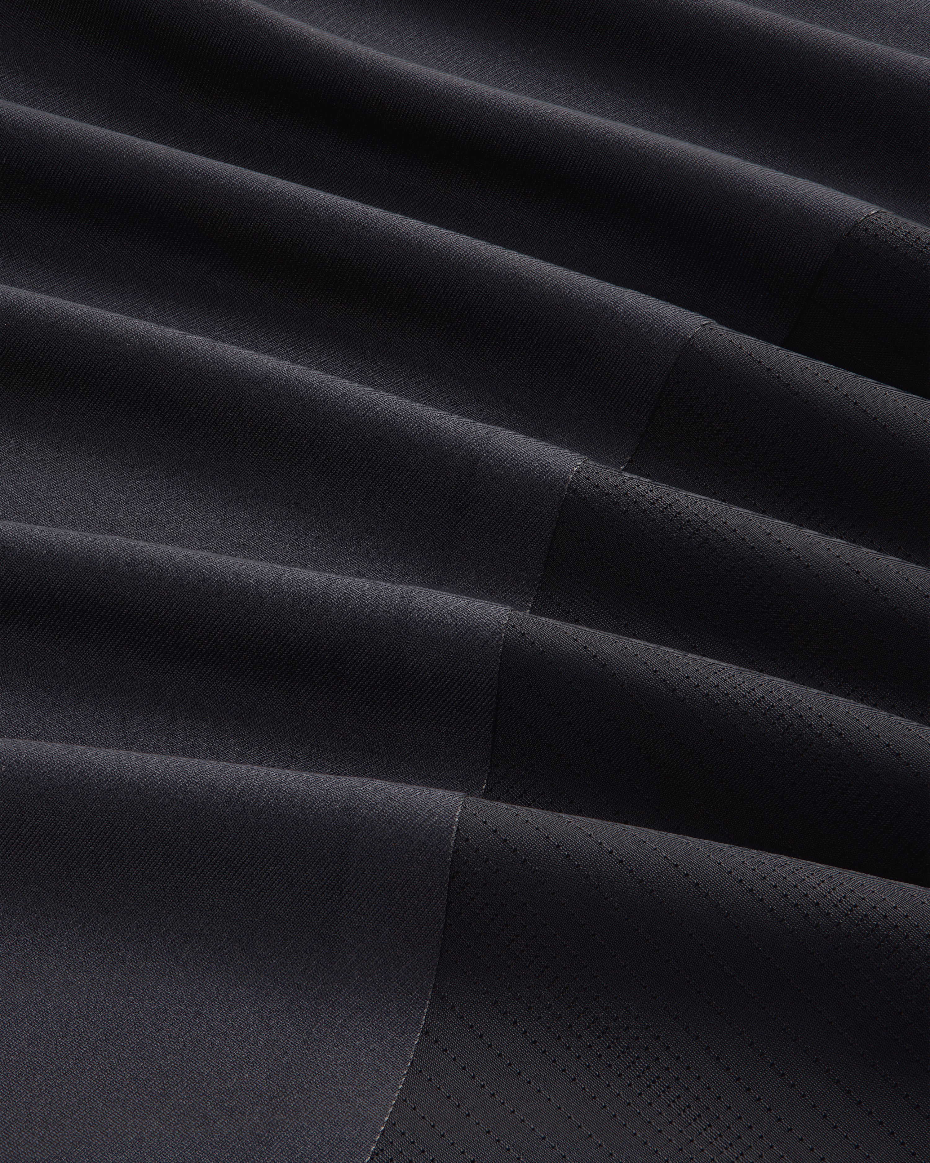 Close-up of the ALD / New Balance Performance Long-Sleeve Tee's dark, pleated fabric with matte and shiny textures.