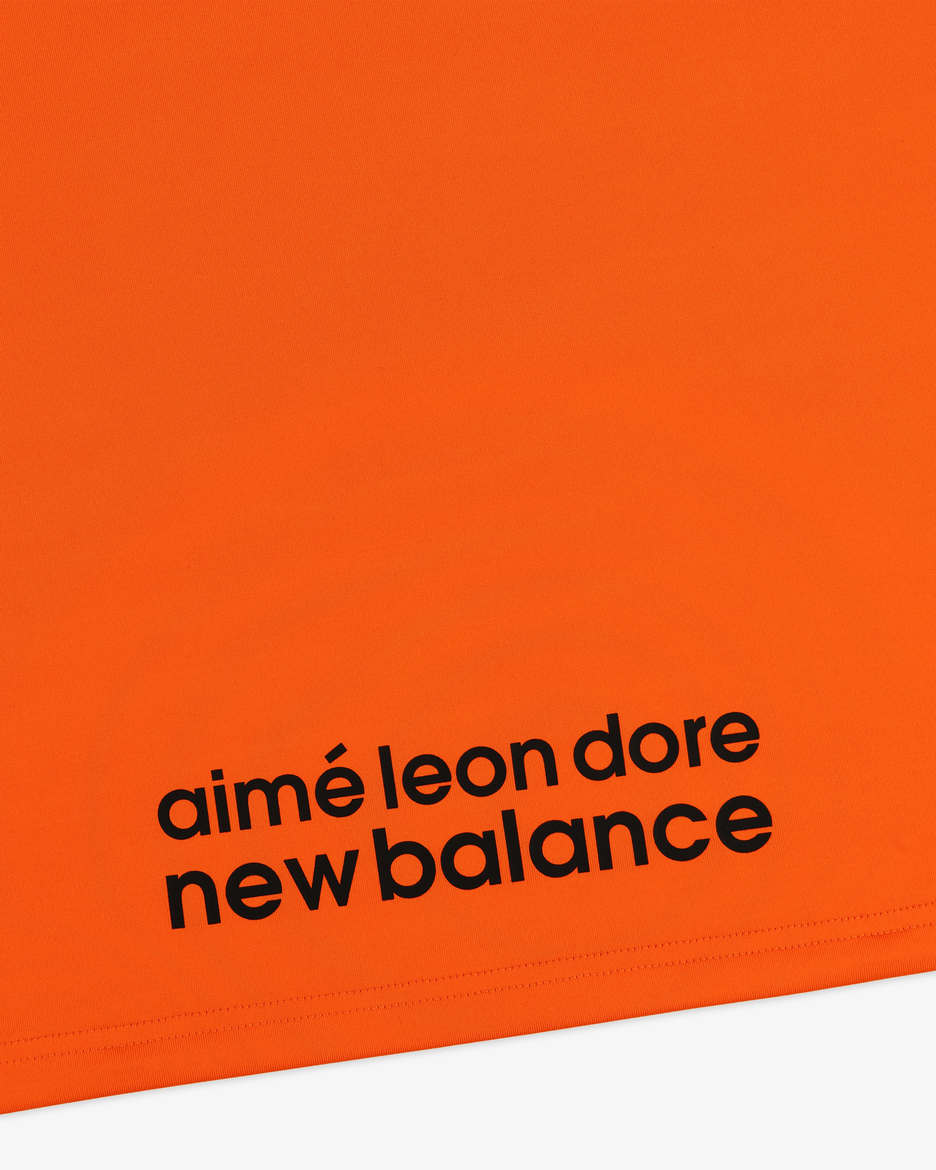 Bright orange ALD / New Balance Performance Long-Sleeve Tee with bold black logo near the bottom edge.
