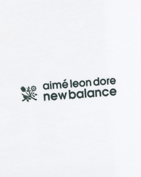 Black ALD / New Balance Running Bib Tee with logo and small flower graphic on white fabric background.