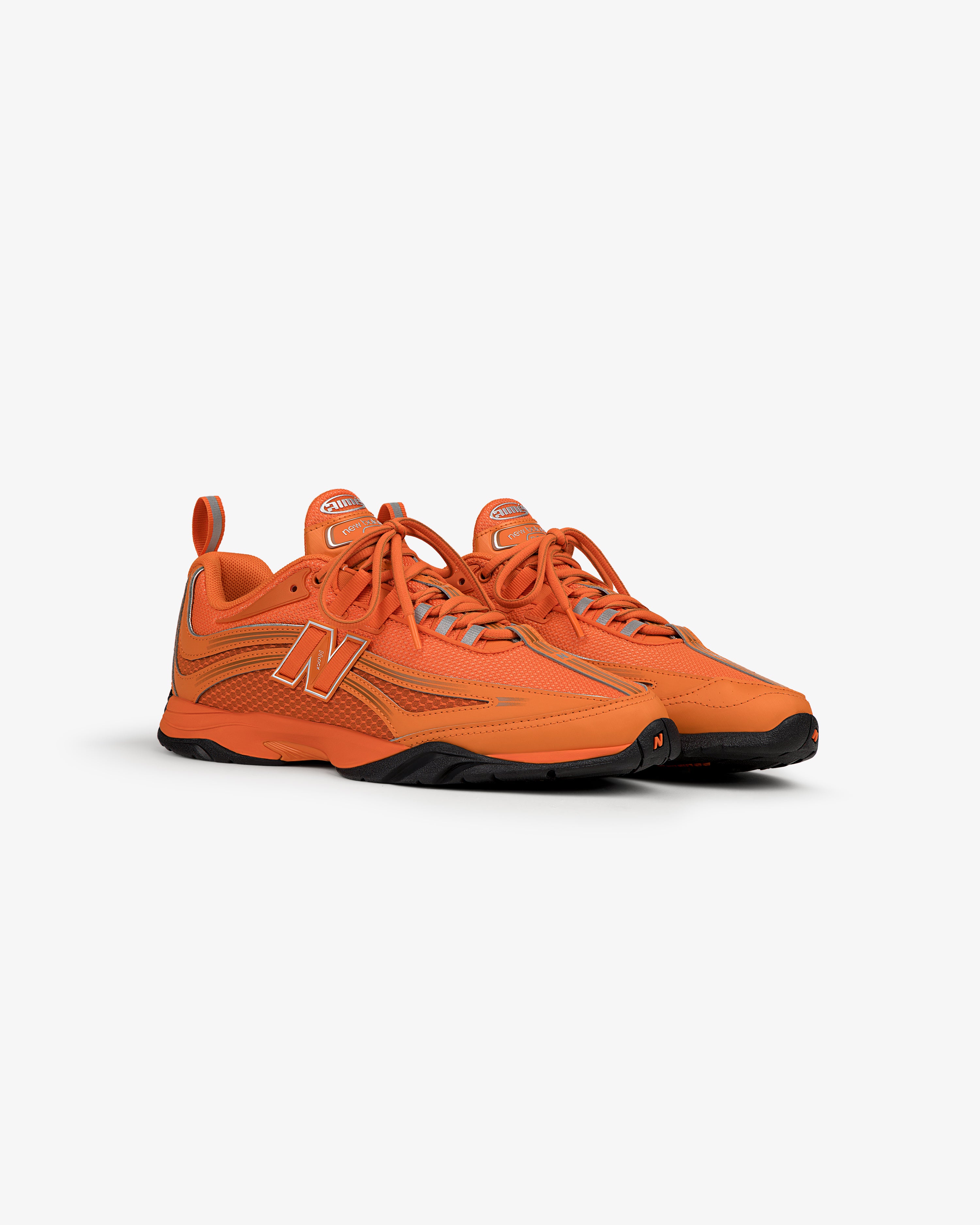 ALD / New Balance RC56 bright orange sneakers with black soles on white background.