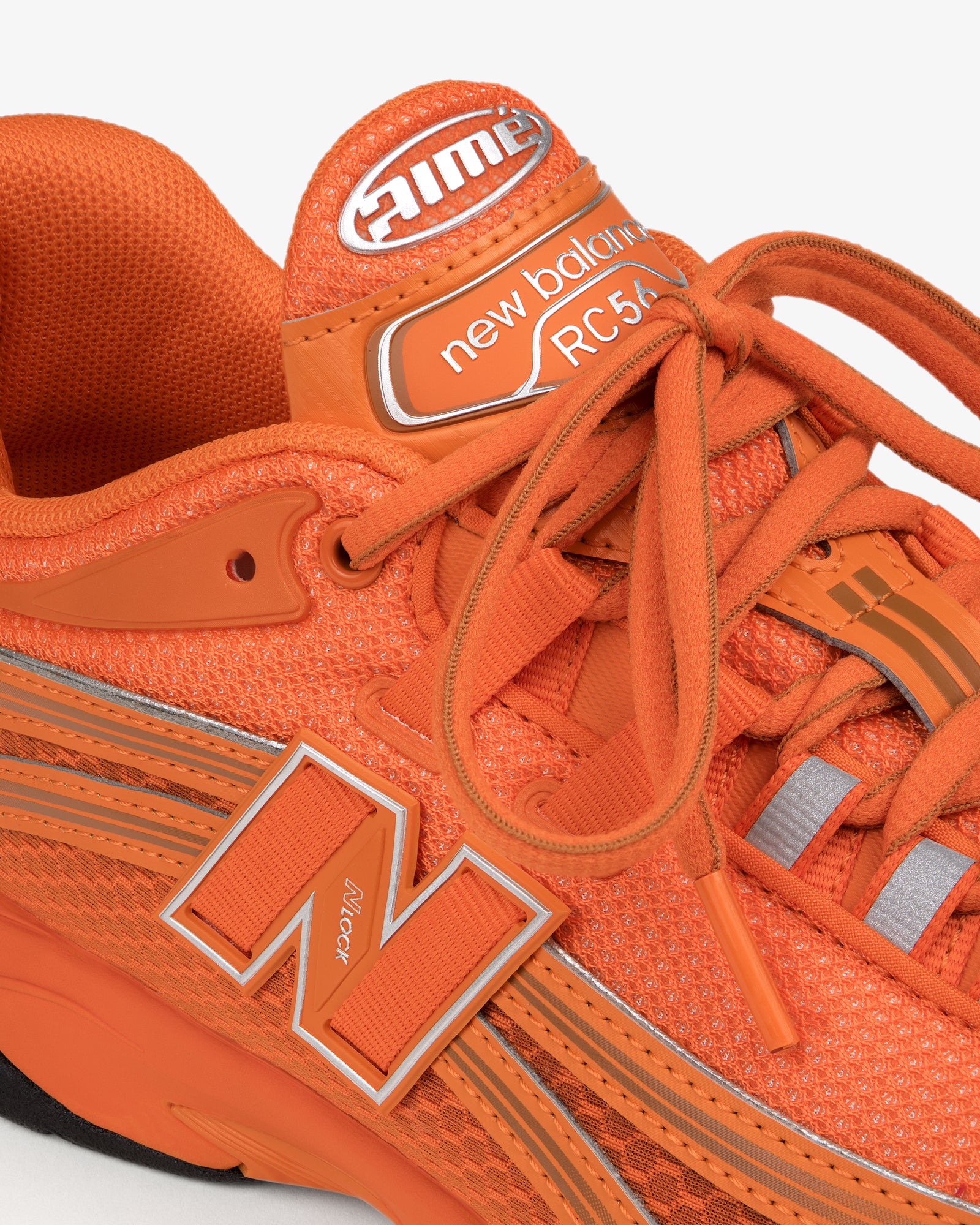 Close-up of an orange ALD / New Balance RC56 sneaker with visible laces and logo.