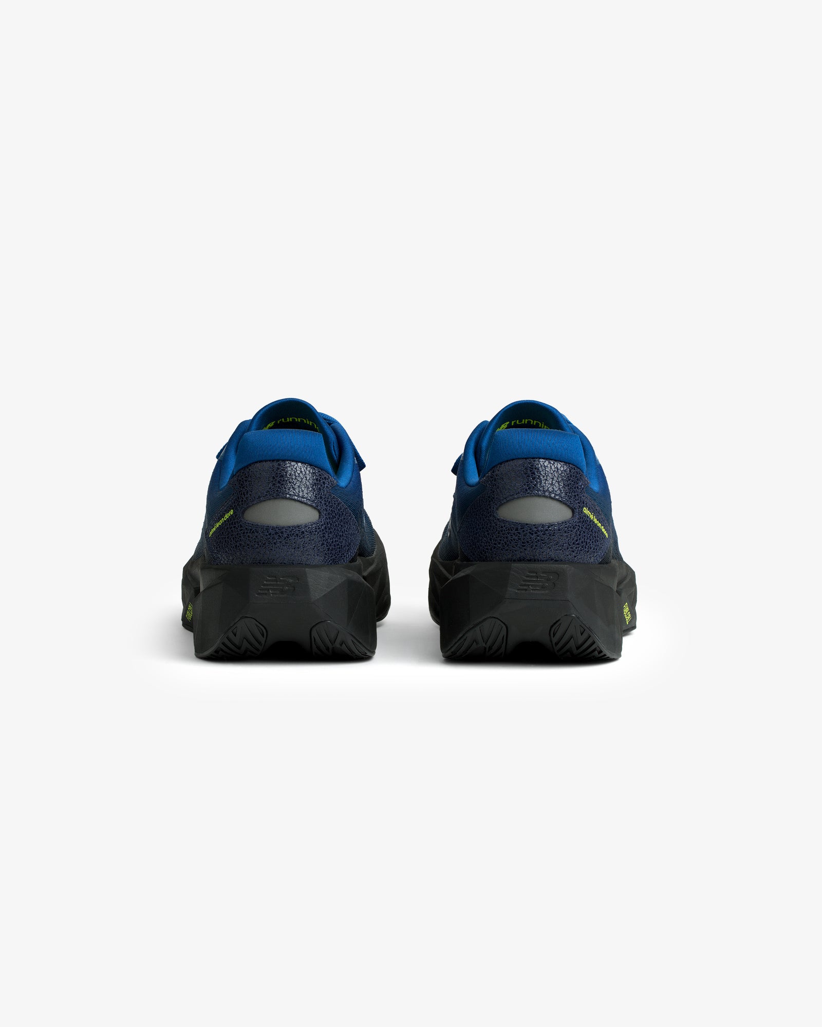 Rear view of ALD / New Balance FuelCell Rebel v5 in blue and black with textured soles on a white background.