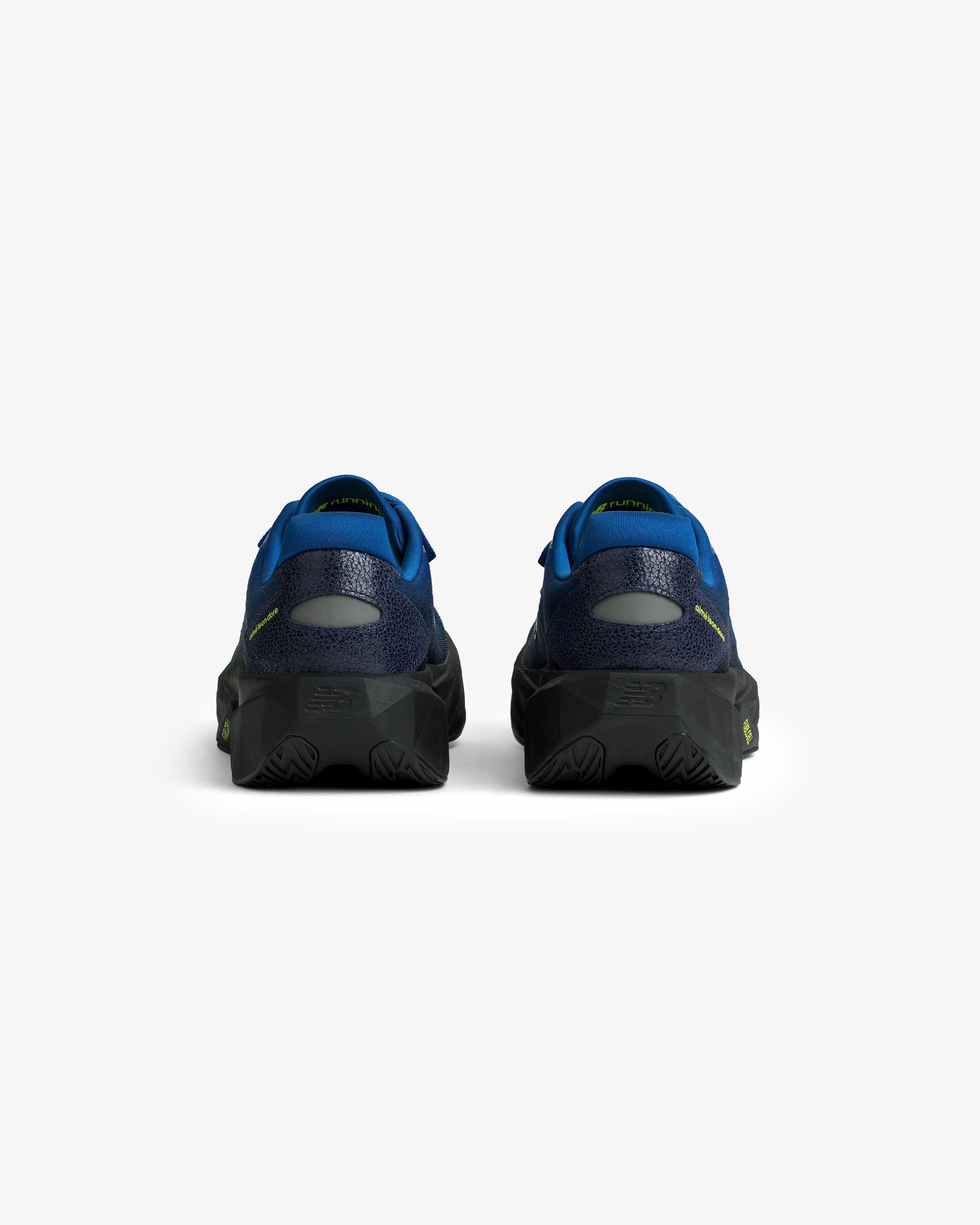 Rear view of ALD / New Balance FuelCell Rebel v5 in blue and black with textured soles on a white background.