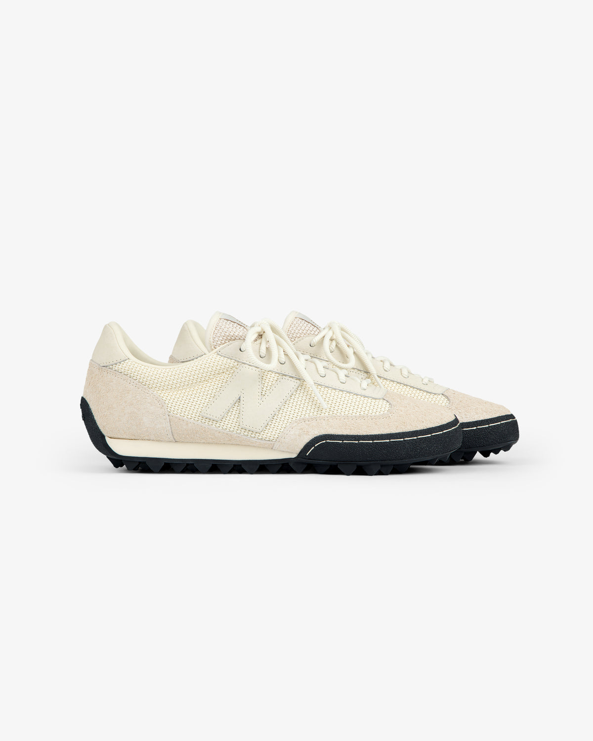 A pair of ALD / New Balance Gator sneakers with textured off-white uppers and black soles on a white background.