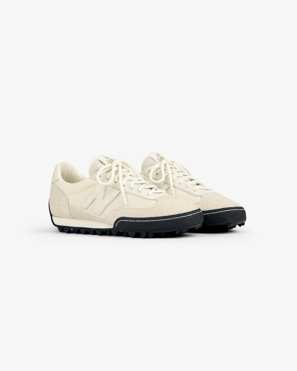 A pair of ALD / New Balance Gator off-white low-top sneakers with textured uppers and black rubber soles.