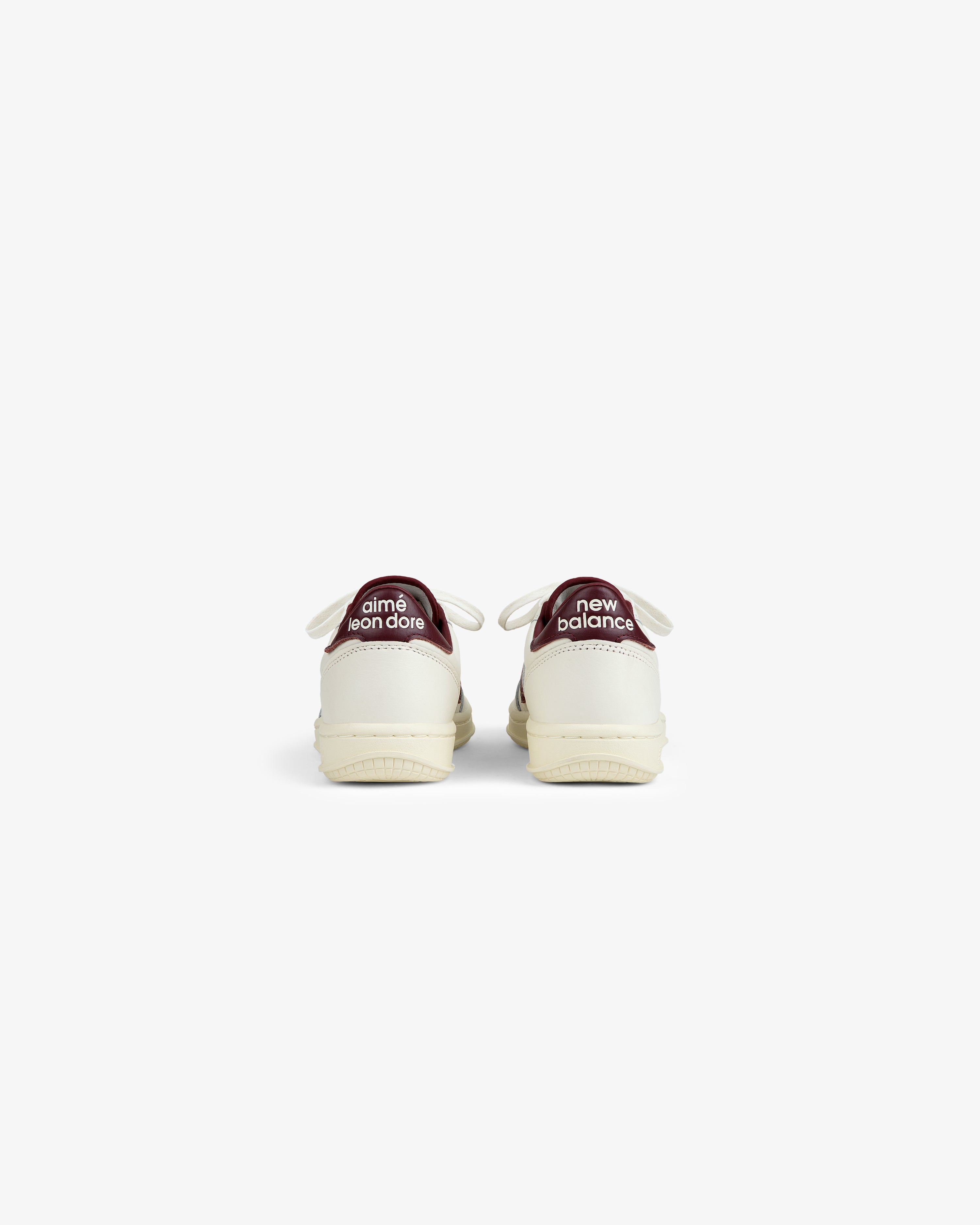Back view of two off-white ALD / New Balance T500 Tennis Oxfords with dark red heel tabs featuring brand text.