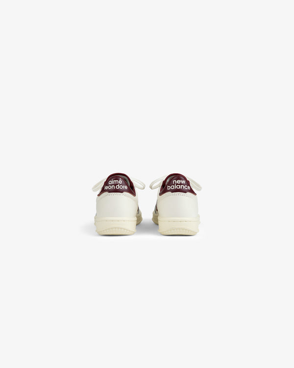 Back view of two off-white ALD / New Balance T500 Tennis Oxfords with dark red heel tabs featuring brand text.