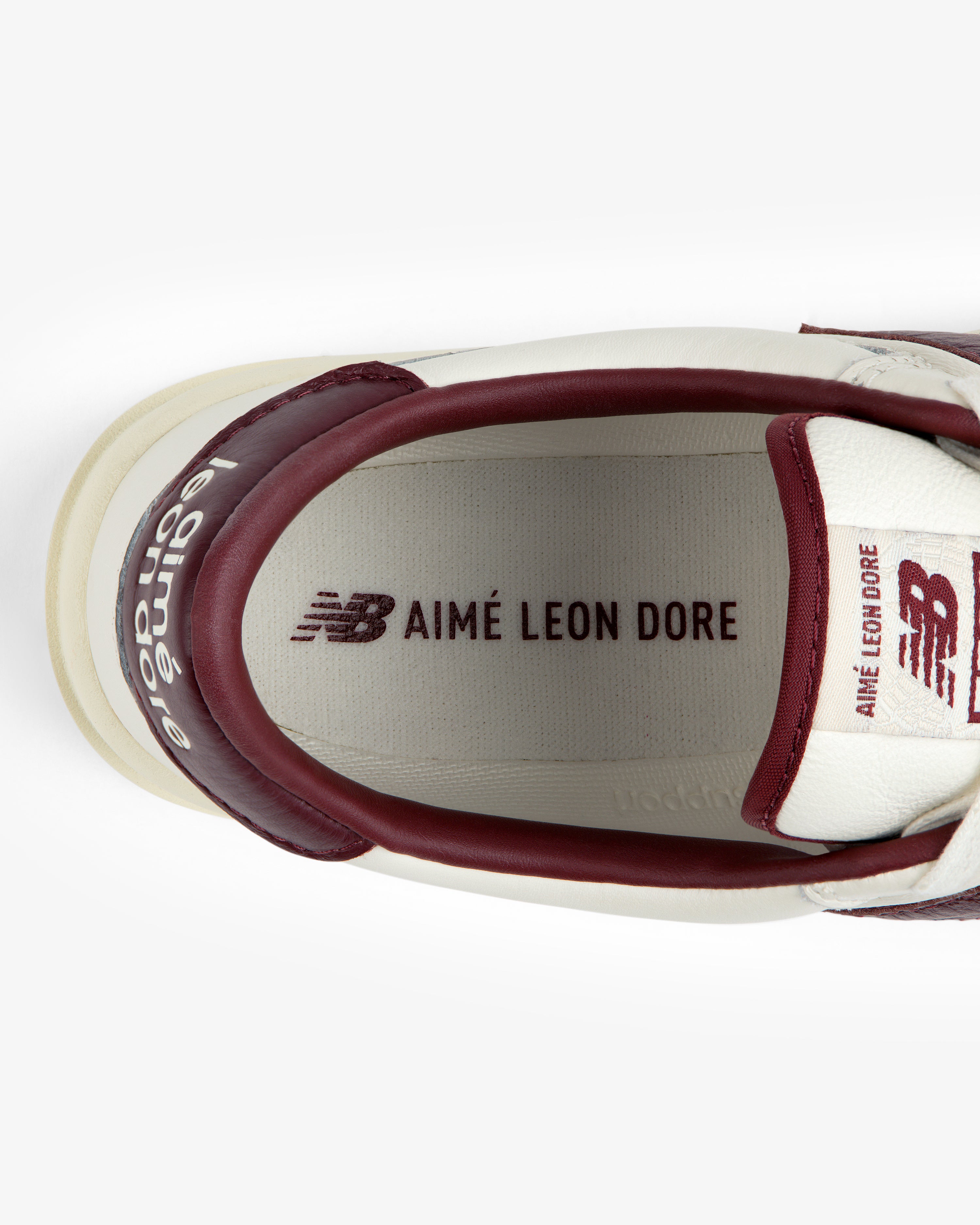 Top-down view of an ALD / New Balance T500 Tennis Oxford white sneaker with red trim and logos on the insole and tongue.