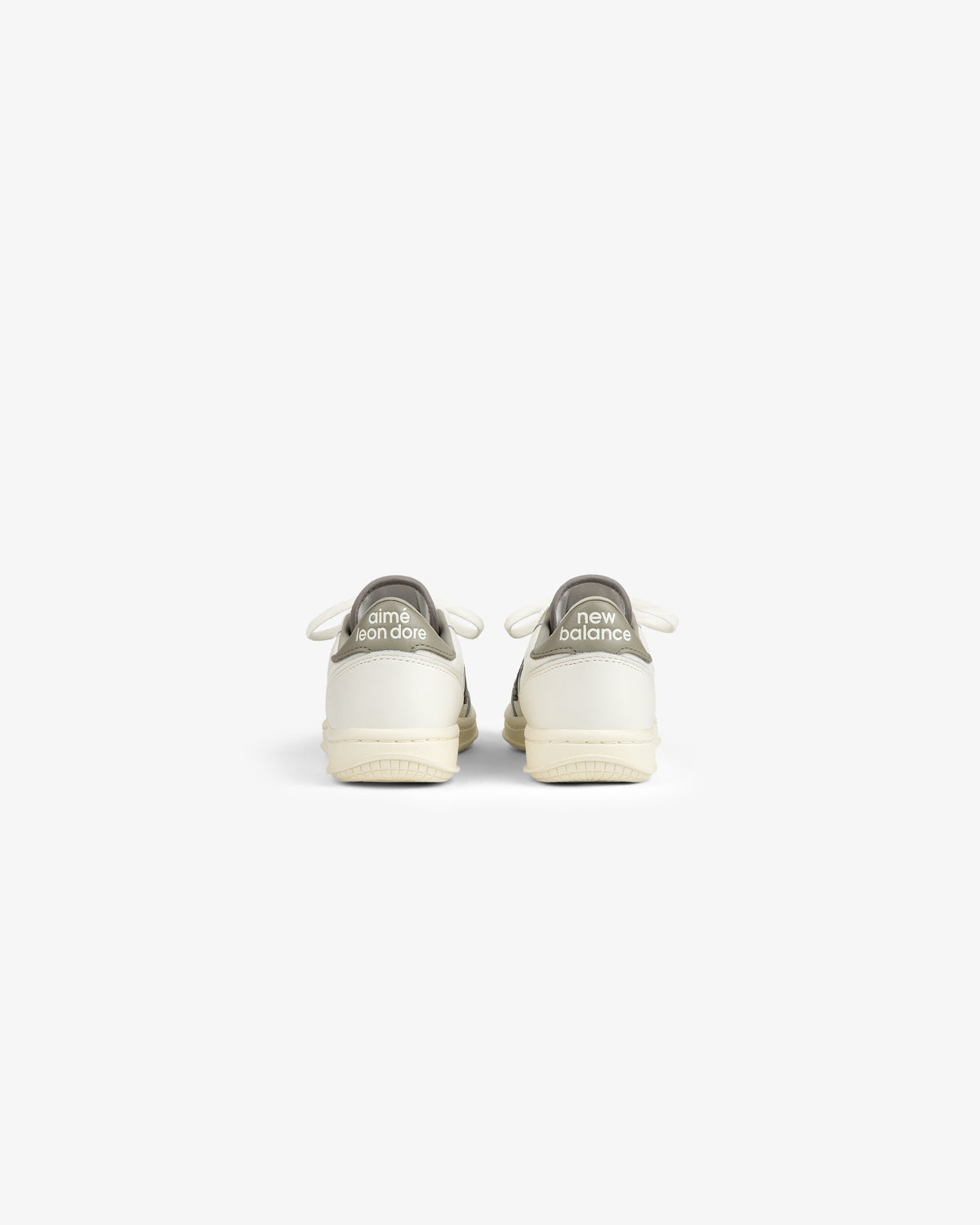 Back view of two white ALD / New Balance T500 Tennis Oxfords with grey heel tabs featuring logo text.