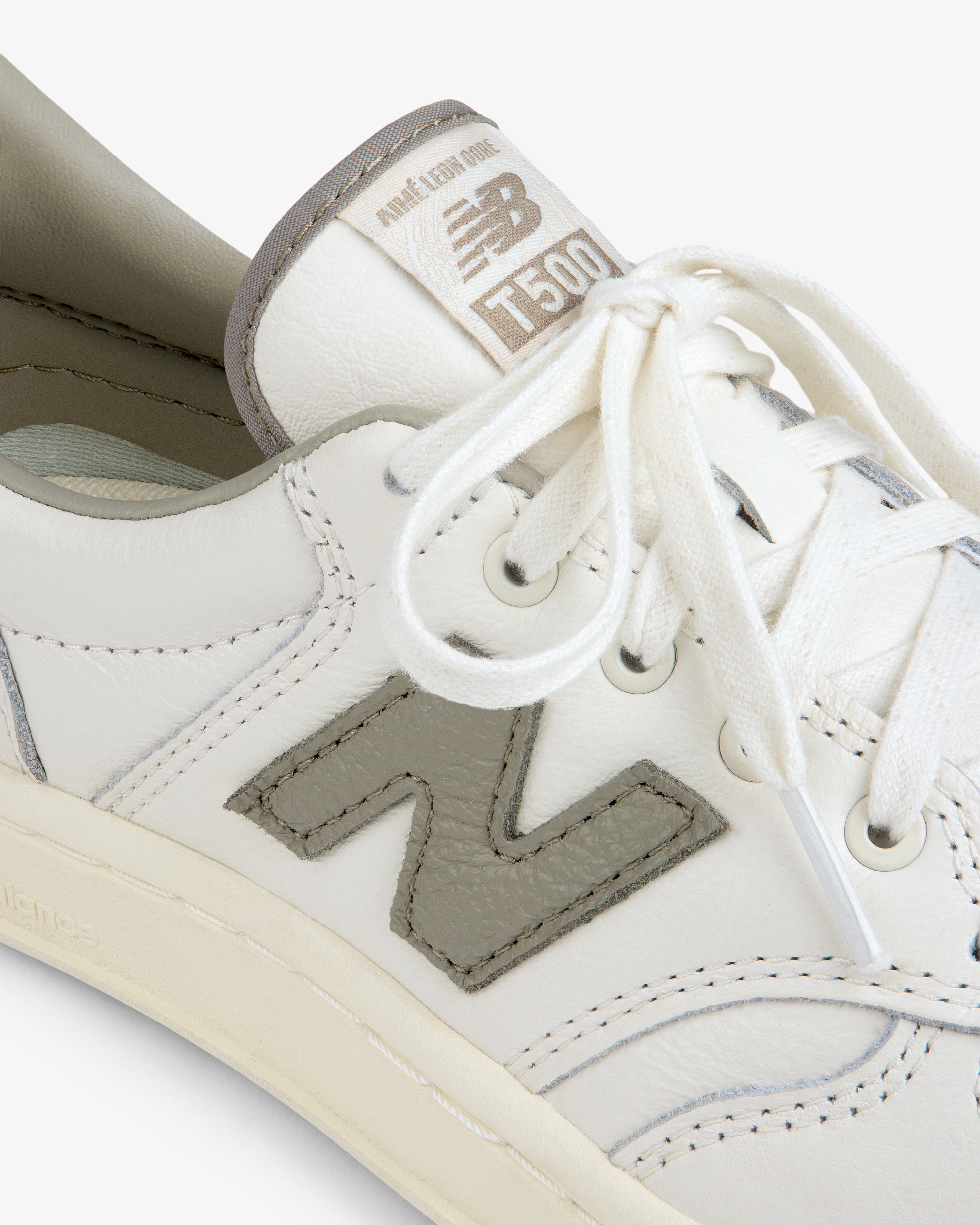 Close-up of a white ALD / New Balance T500 Tennis Oxford sneaker with a grey logo patch and matching tongue label.
