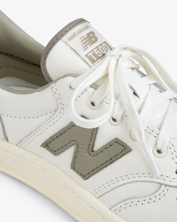 Close-up of a white ALD / New Balance T500 Tennis Oxford sneaker with a grey logo patch and matching tongue label.