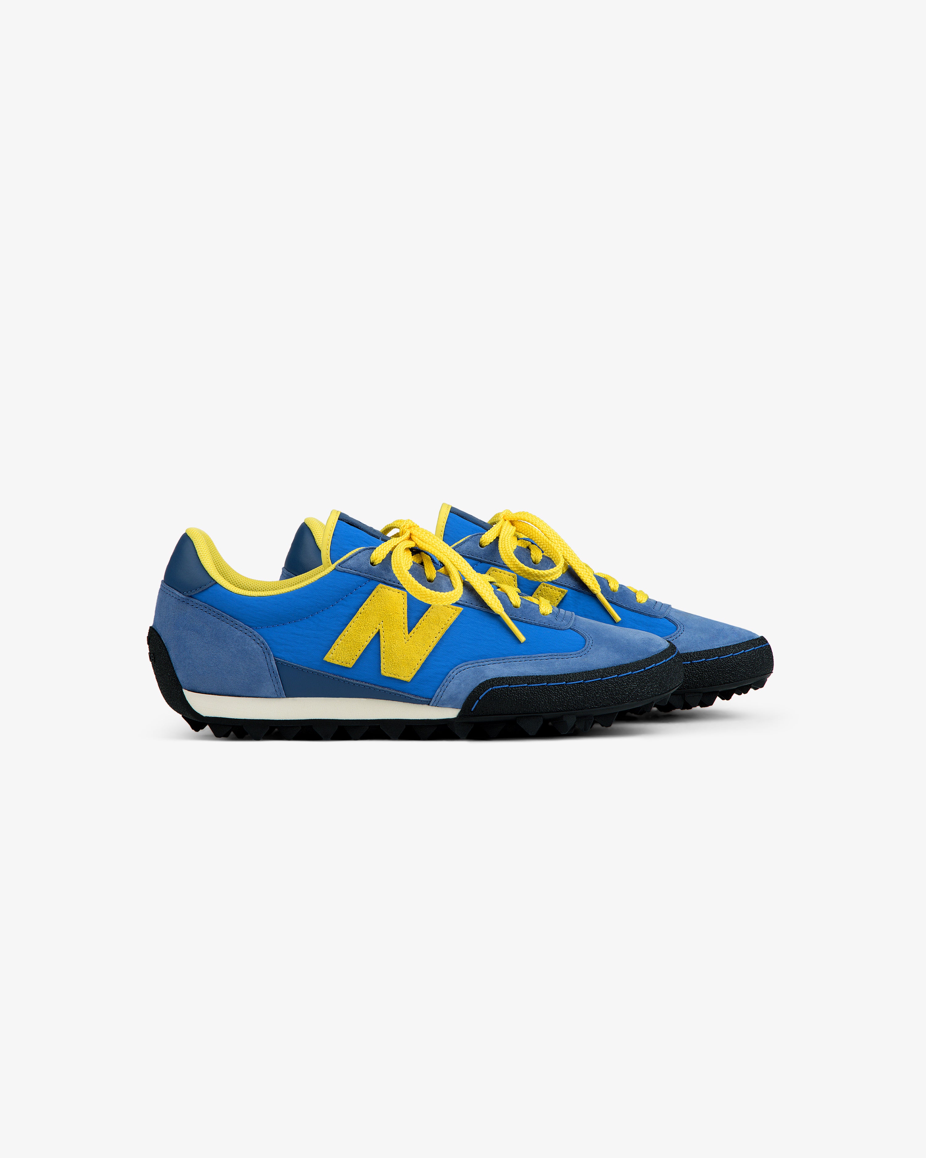 ALD / New Balance Gator blue low-top sneaker with a yellow logo, yellow laces, and a black lugged sole.