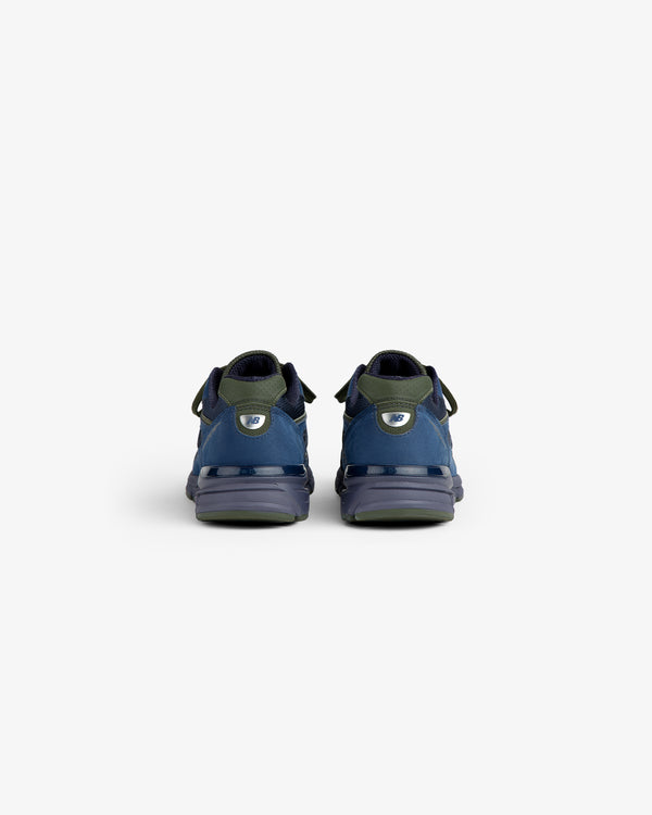 New Balance Made in USA 990v4 sneakers in blue and green, shown from the back on a white background.