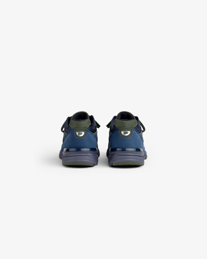 New Balance Made in USA 990v4 sneakers in blue and green, shown from the back on a white background.