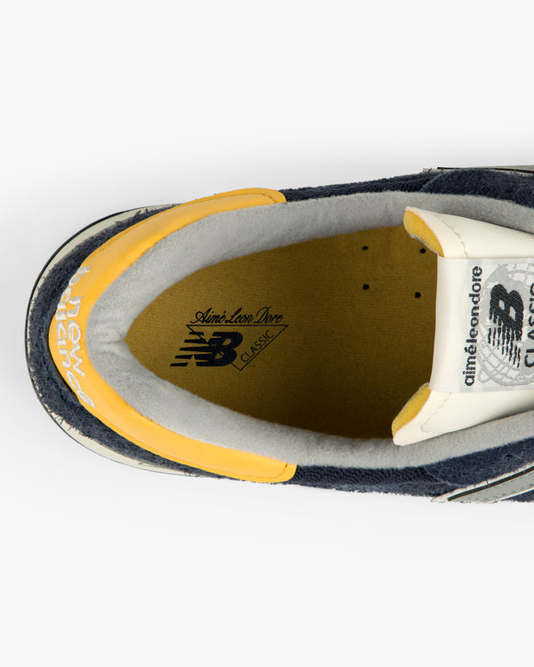 Top view of the ALD / New Balance Made in USA 1300 sneaker with branding on the insole and yellow, gray, navy accents.