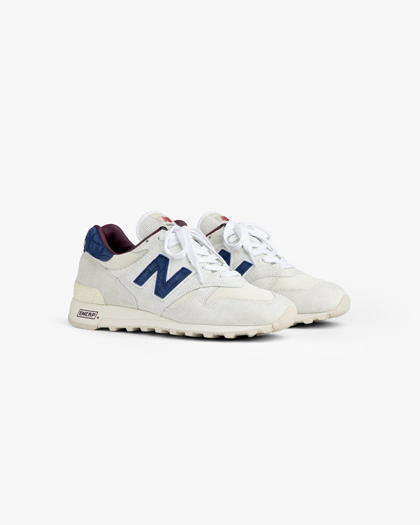 New Balance Made in USA 1300: white sneakers with navy N logo, maroon accents, off-white soles on white background.