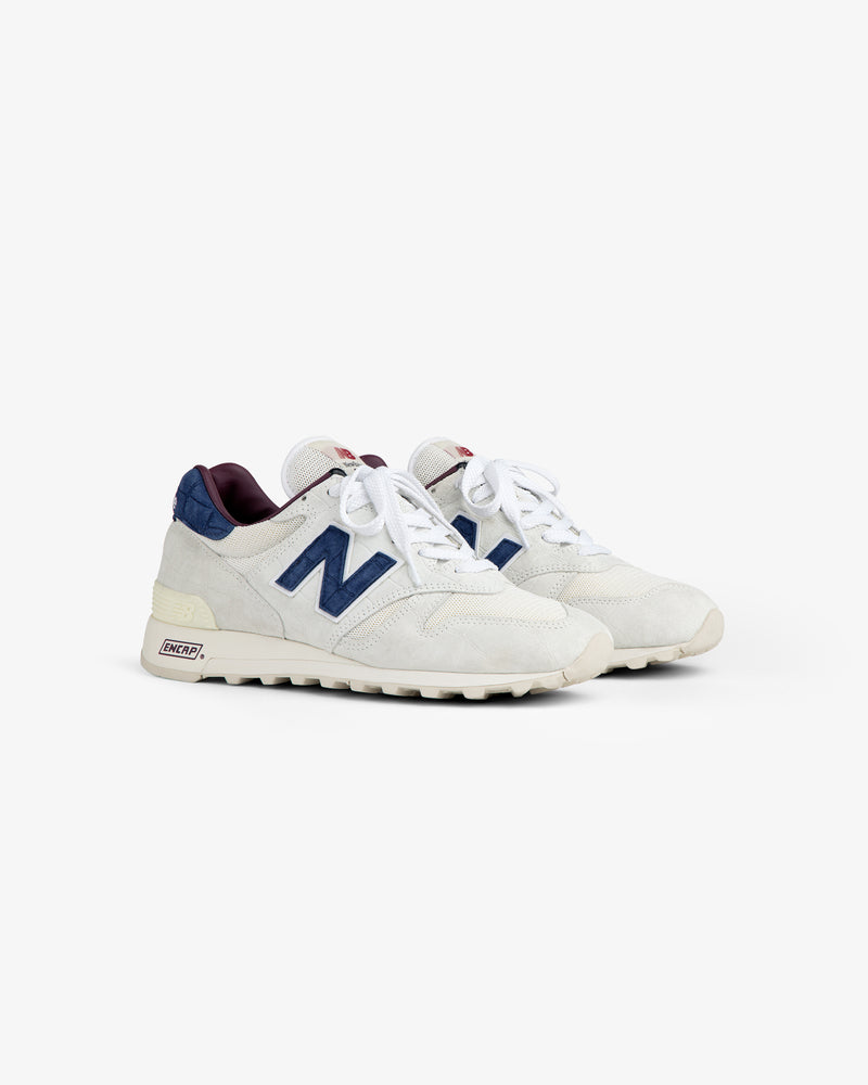 New Balance Made in USA 1300: white sneakers with navy N logo, maroon accents, off-white soles on white background.